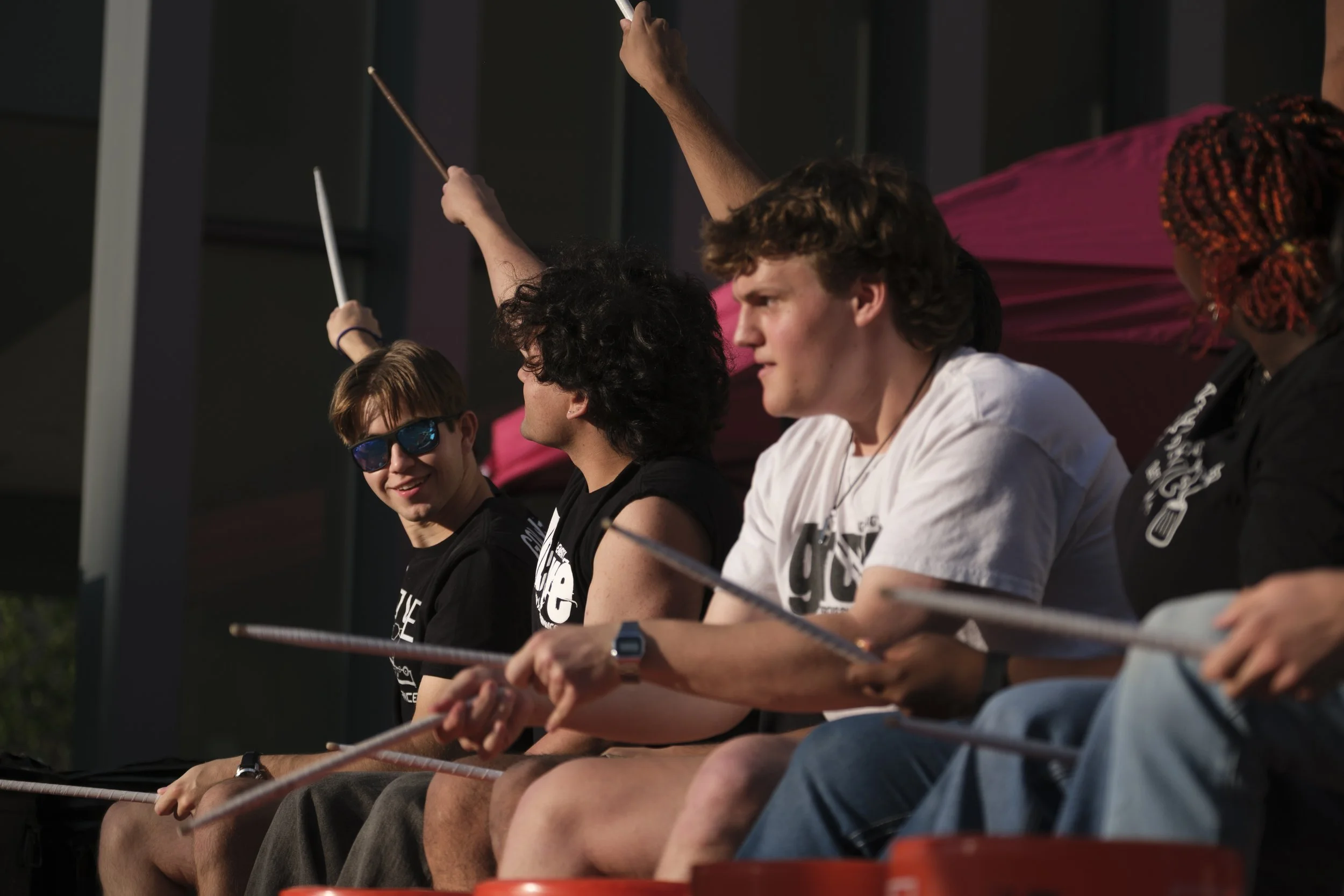 A member of the group Groove wearing sunglasses and points with his drumsticks while smiling at other drummers during a performance during Artscapade in front of UMMA. .JPG