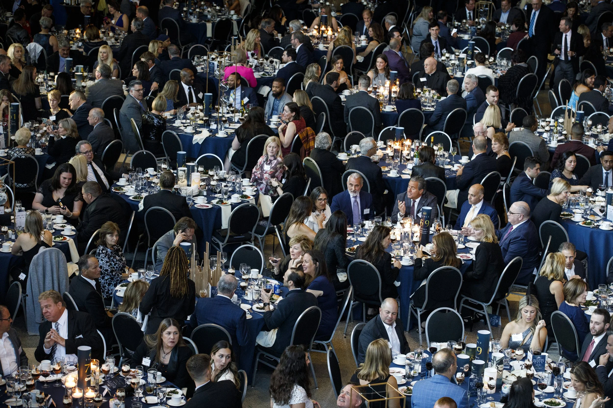 A group of people talking to one another dress in suits and gowns at a gala event.