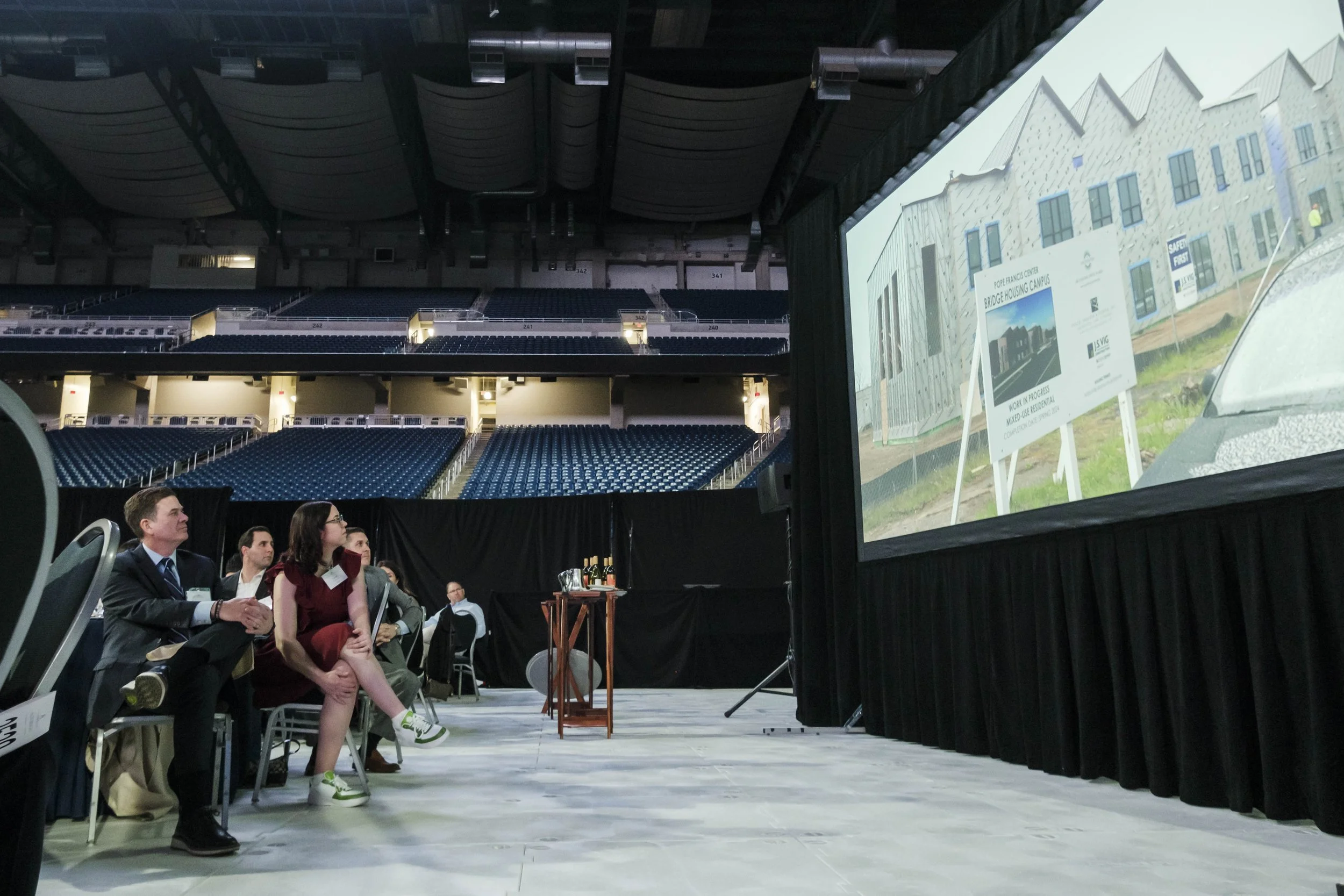 A crowd of people watch a video of a construction project.