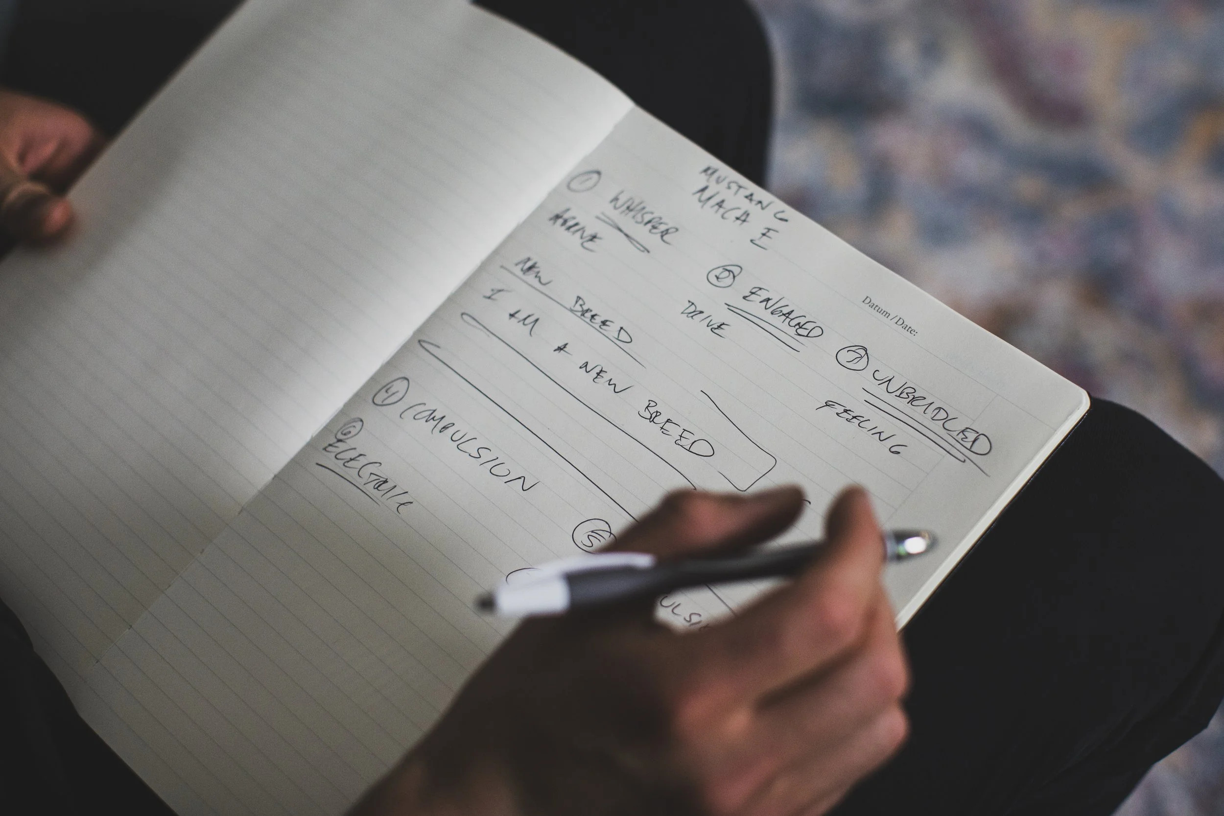 A close up of notes in a notebook with a hand holding a pen.