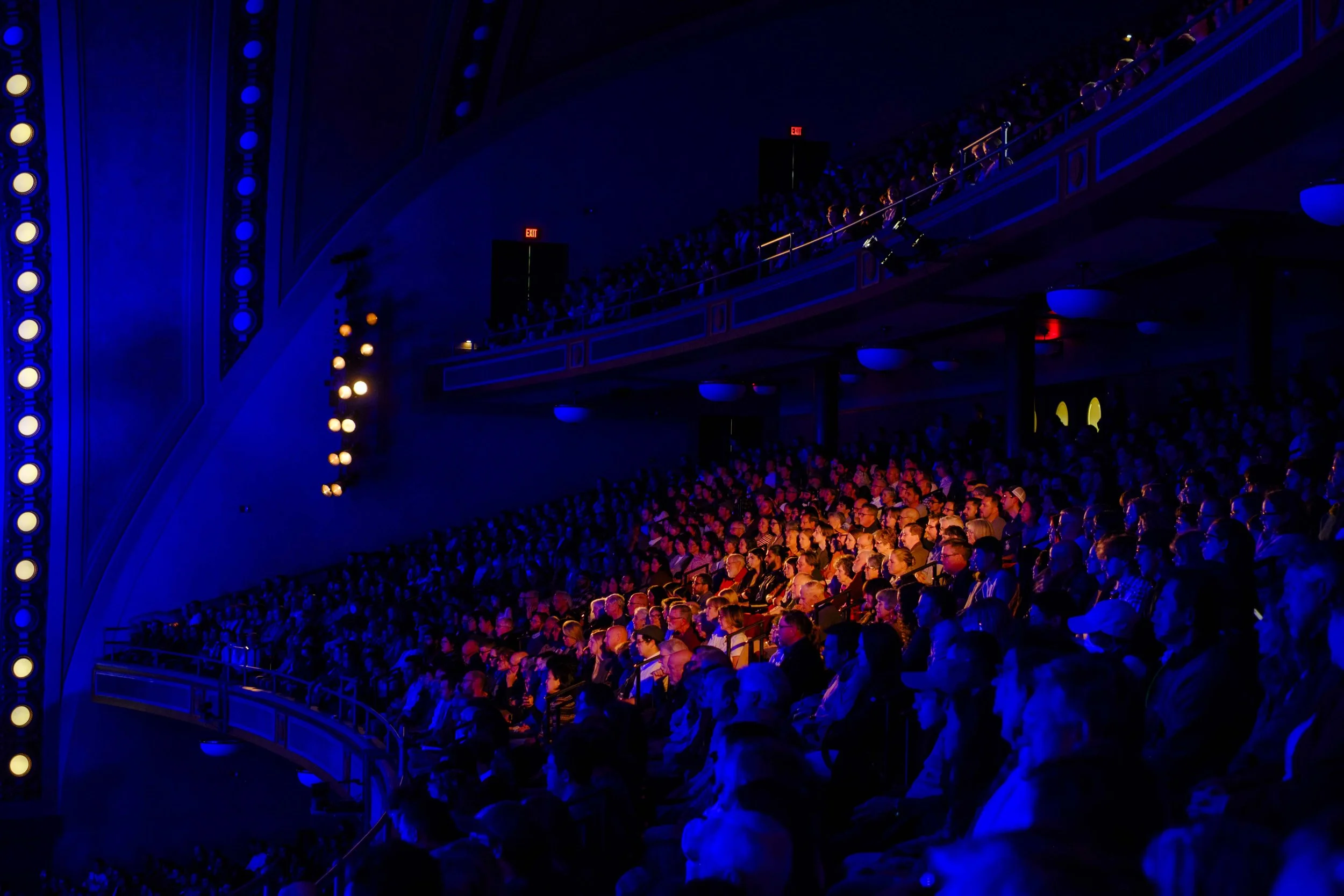 The audience being illuminated by blue and an orange spotlight during a concert with the Ann Arbor Symphony Orchestra