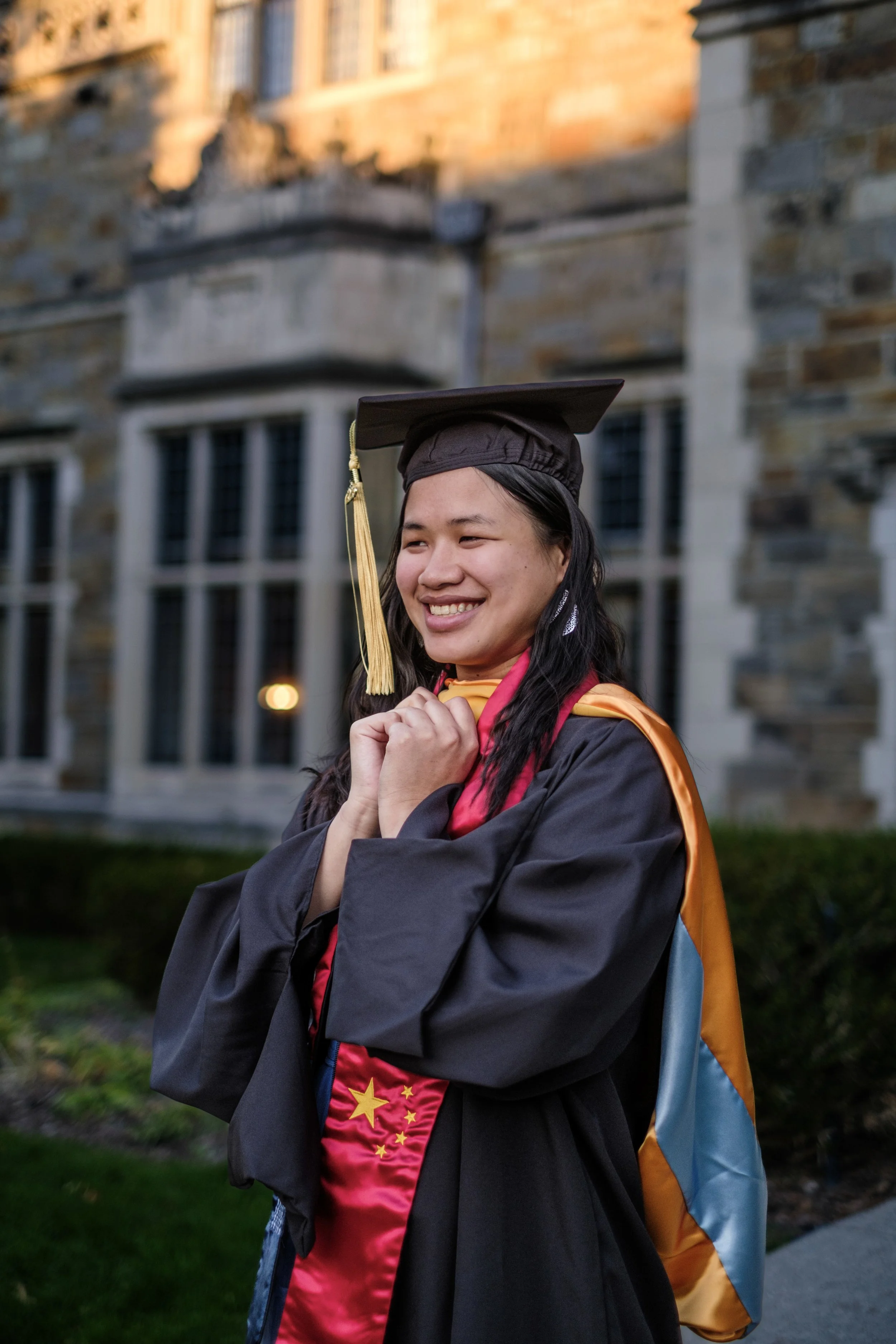 A graduate poses in her gown outside of the Law Quad on campus in Ann Arbor, MI