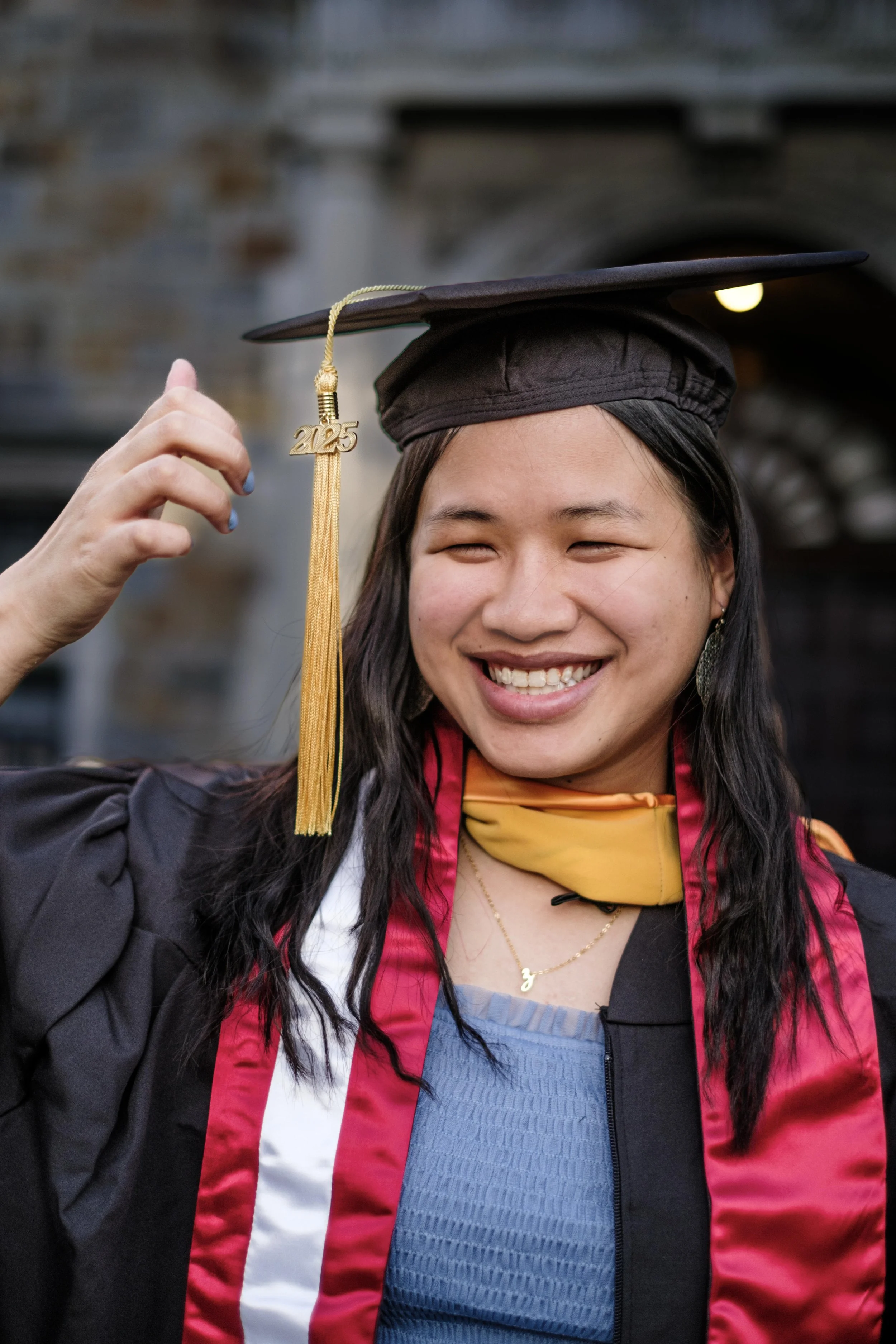 A University of Michigan graduate smiles while posing in her cap and gown on campus in Ann Arbor, Michigan.