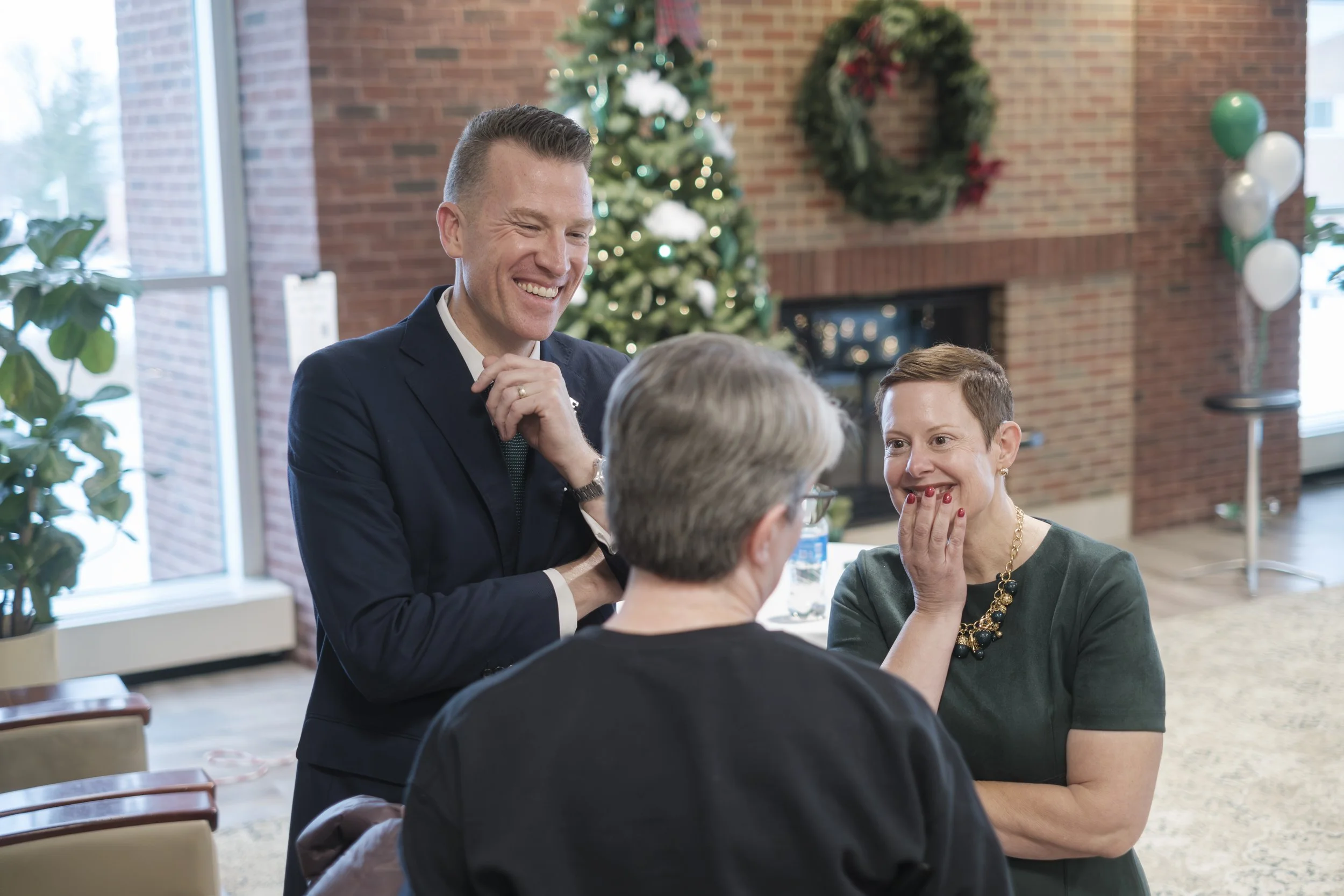 Dr. Brendan Kelly and Dr. Tressa Kelly smiling with a person during a Meet and Greet at Eastern Michigan University.