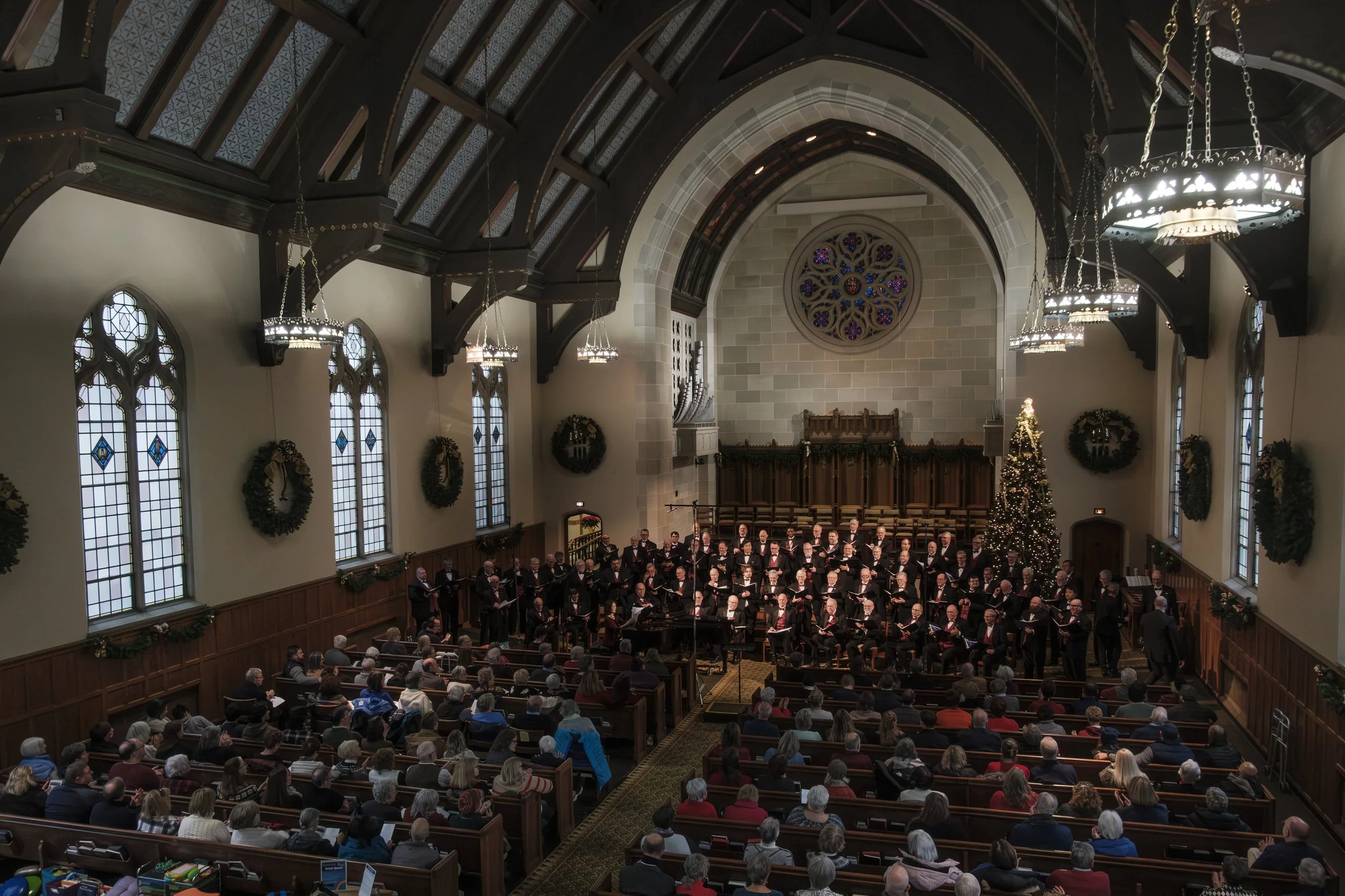 A wide shot of the Measure for Measure men's choir singing on stage at the First United Methodist Church of Ann Arbor