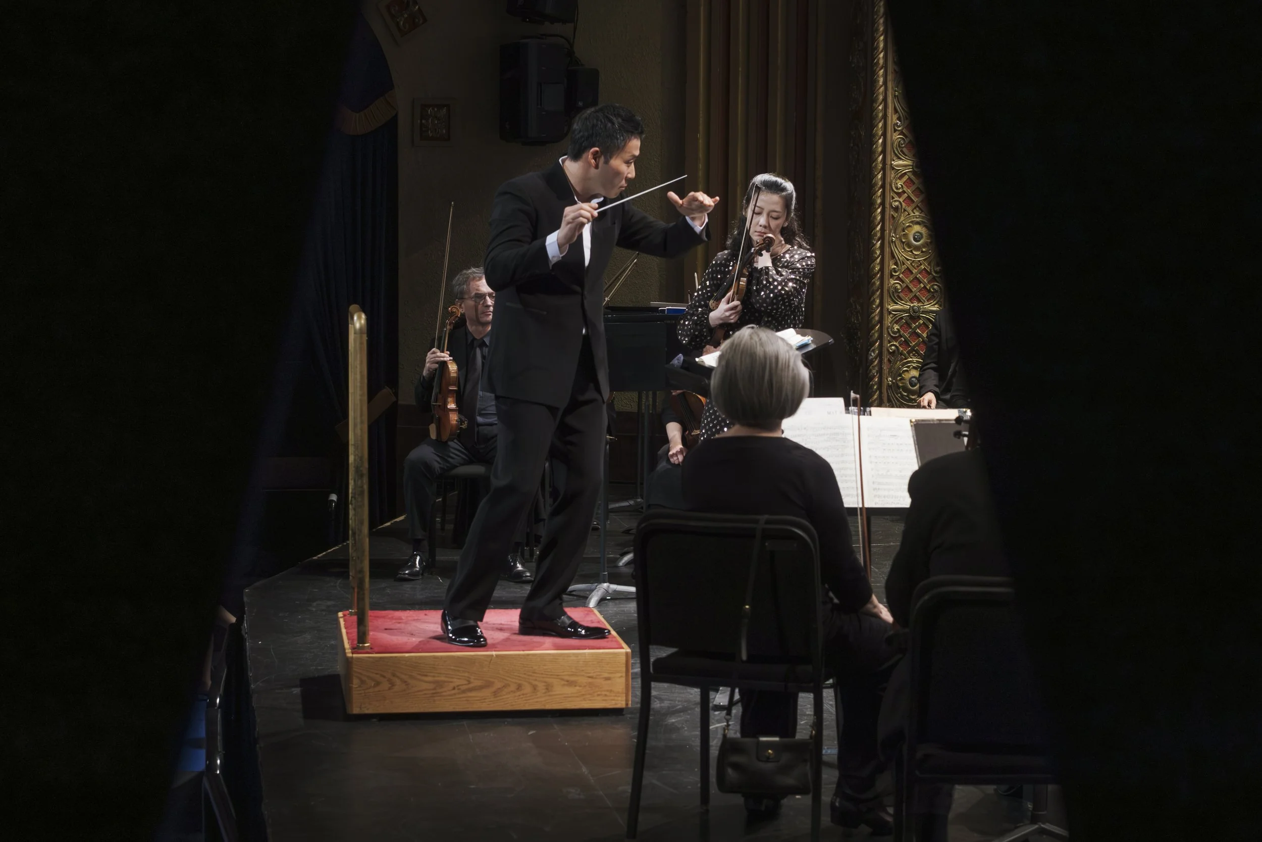 A concert taking place on stage at the Michigan Theater, framed between curtains.