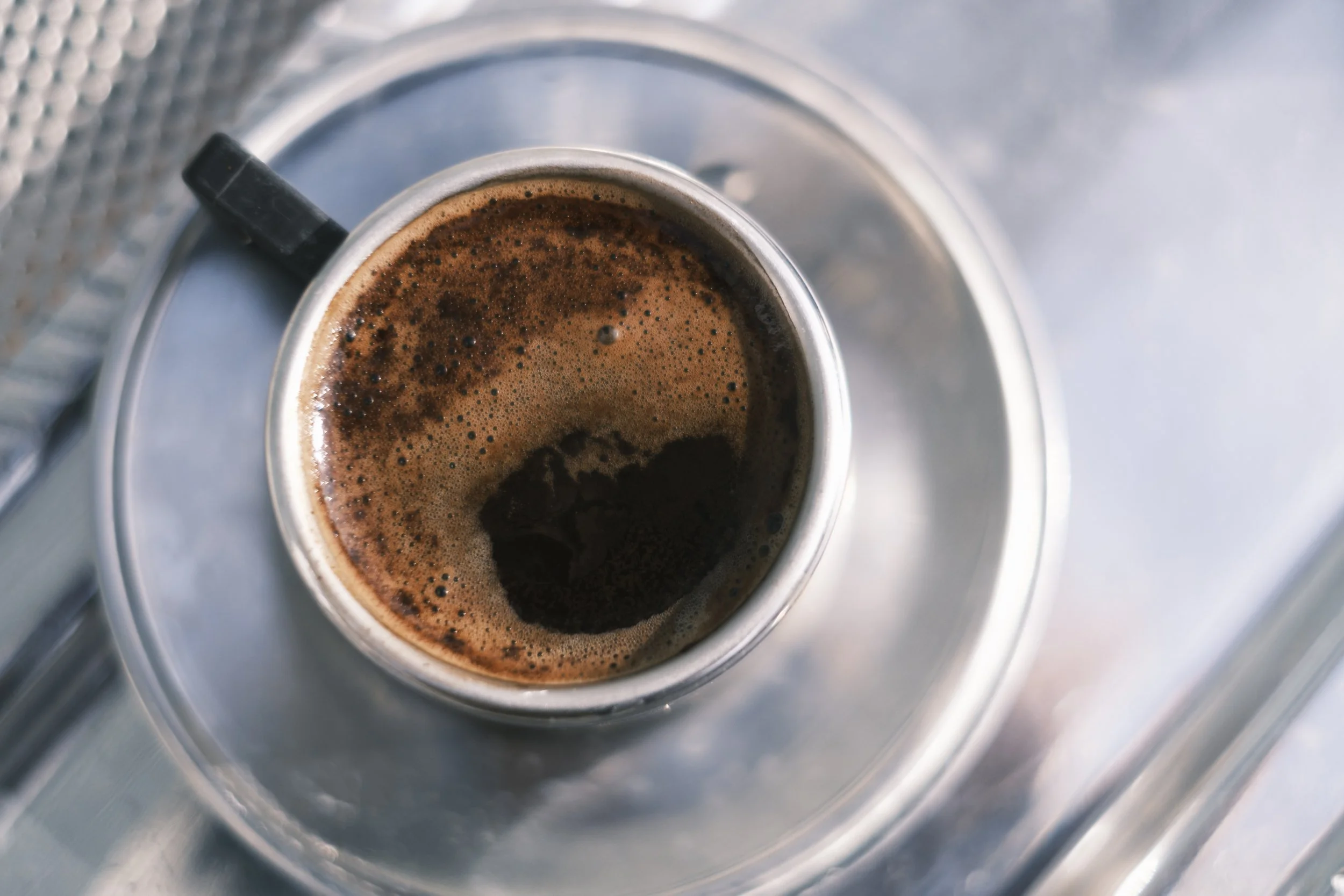 A top down cup of coffee in a stainless steel cup.