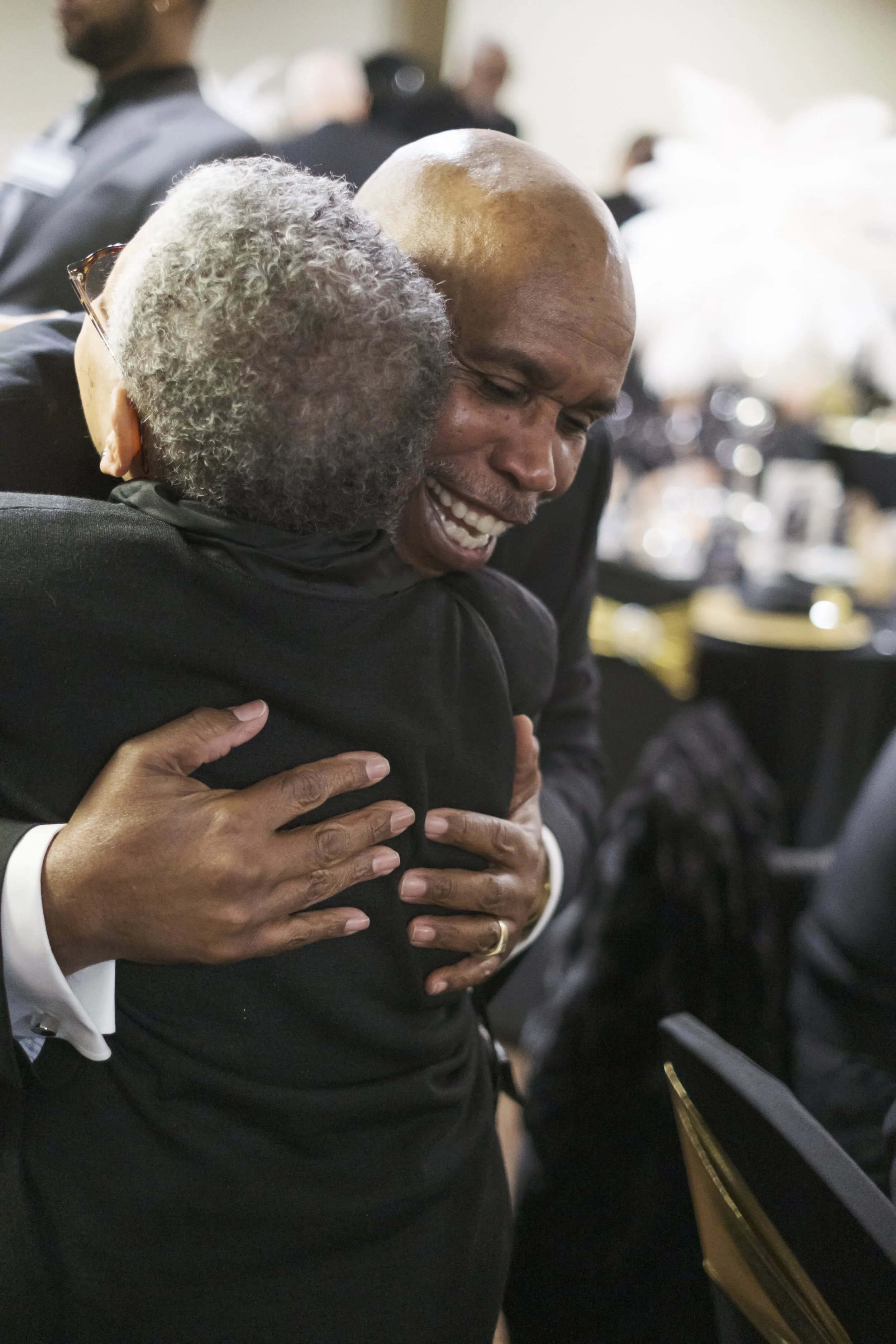 A man hugs a person at a party.