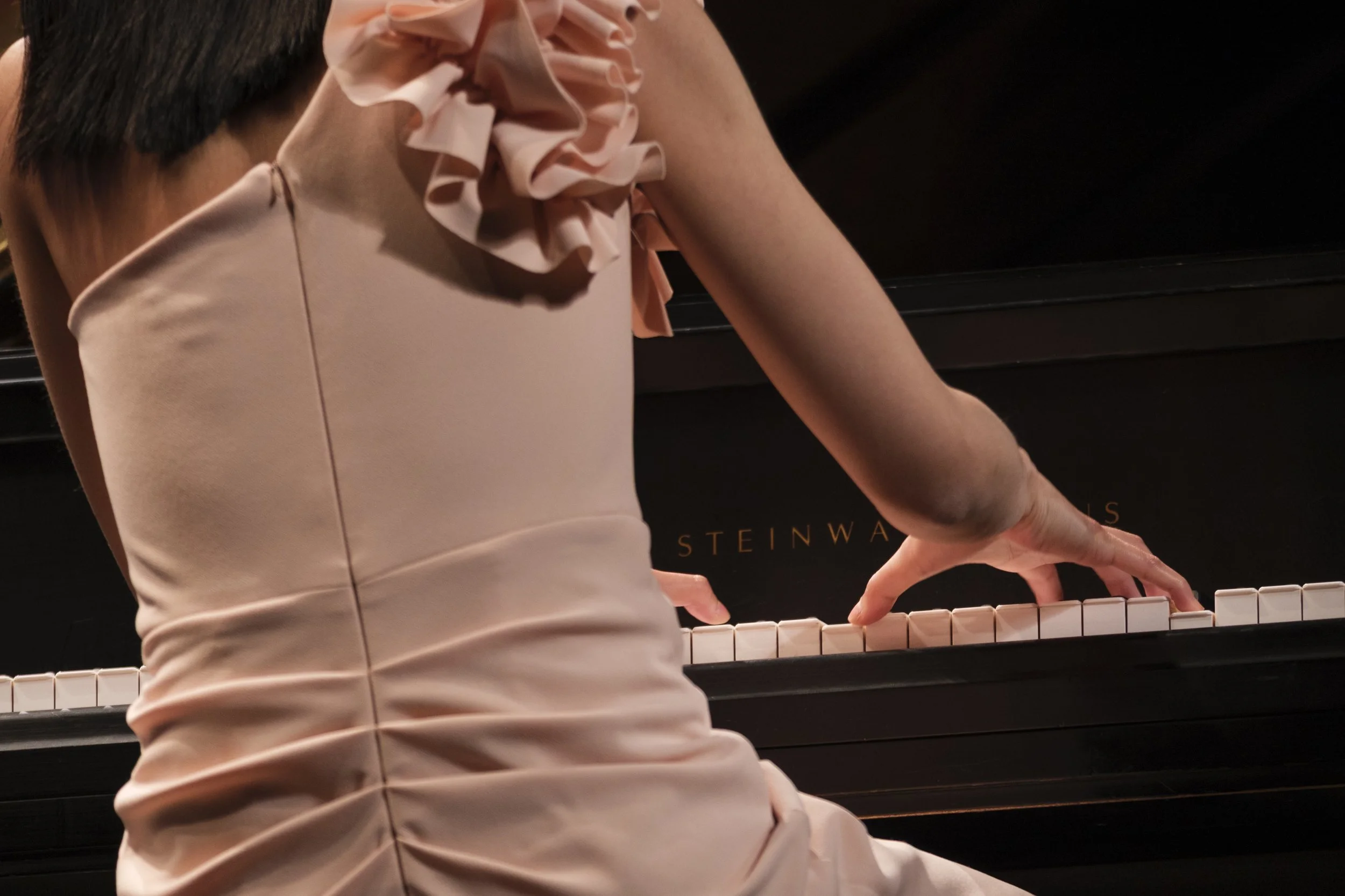 A pianist with her hands on piano keys during a concert.