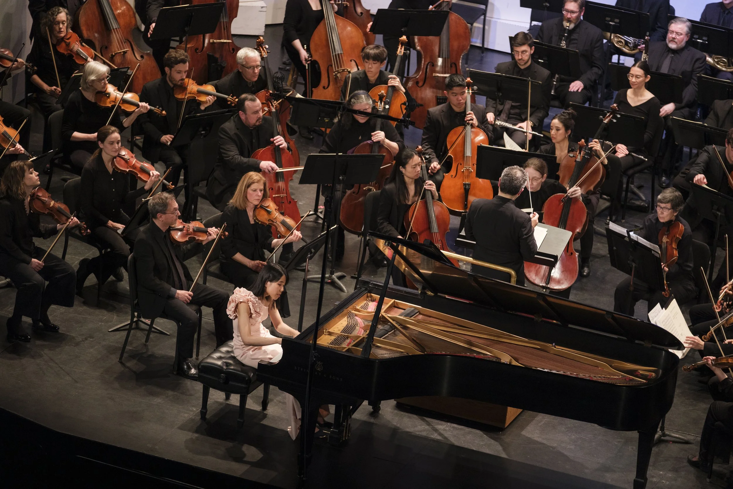 Pianist Kate Liu on stage during a concert with the Ann Arbor Symphony Orchestra surrounding her.