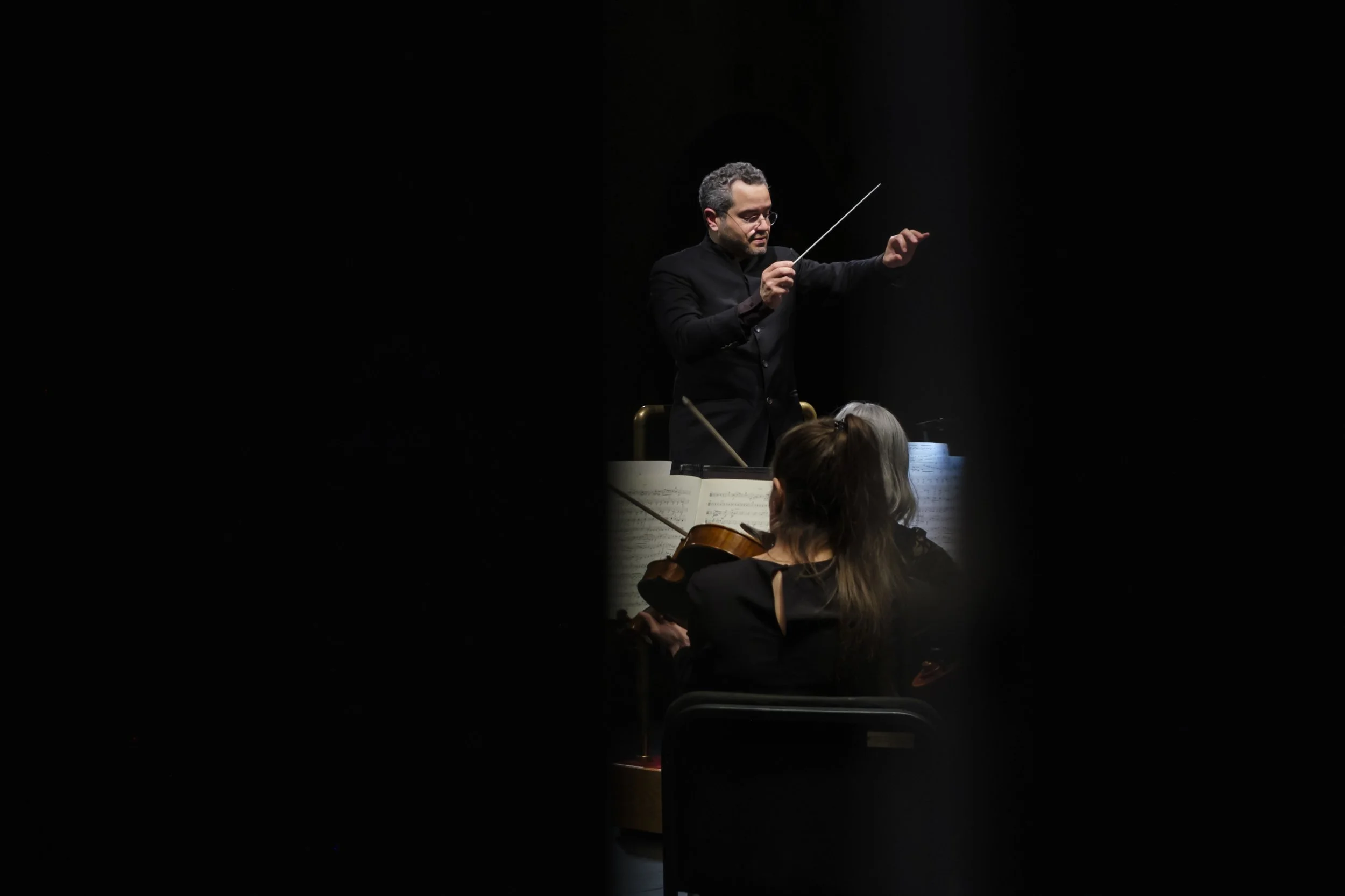 A view behind the scene view of a conductor between curtains while on sta