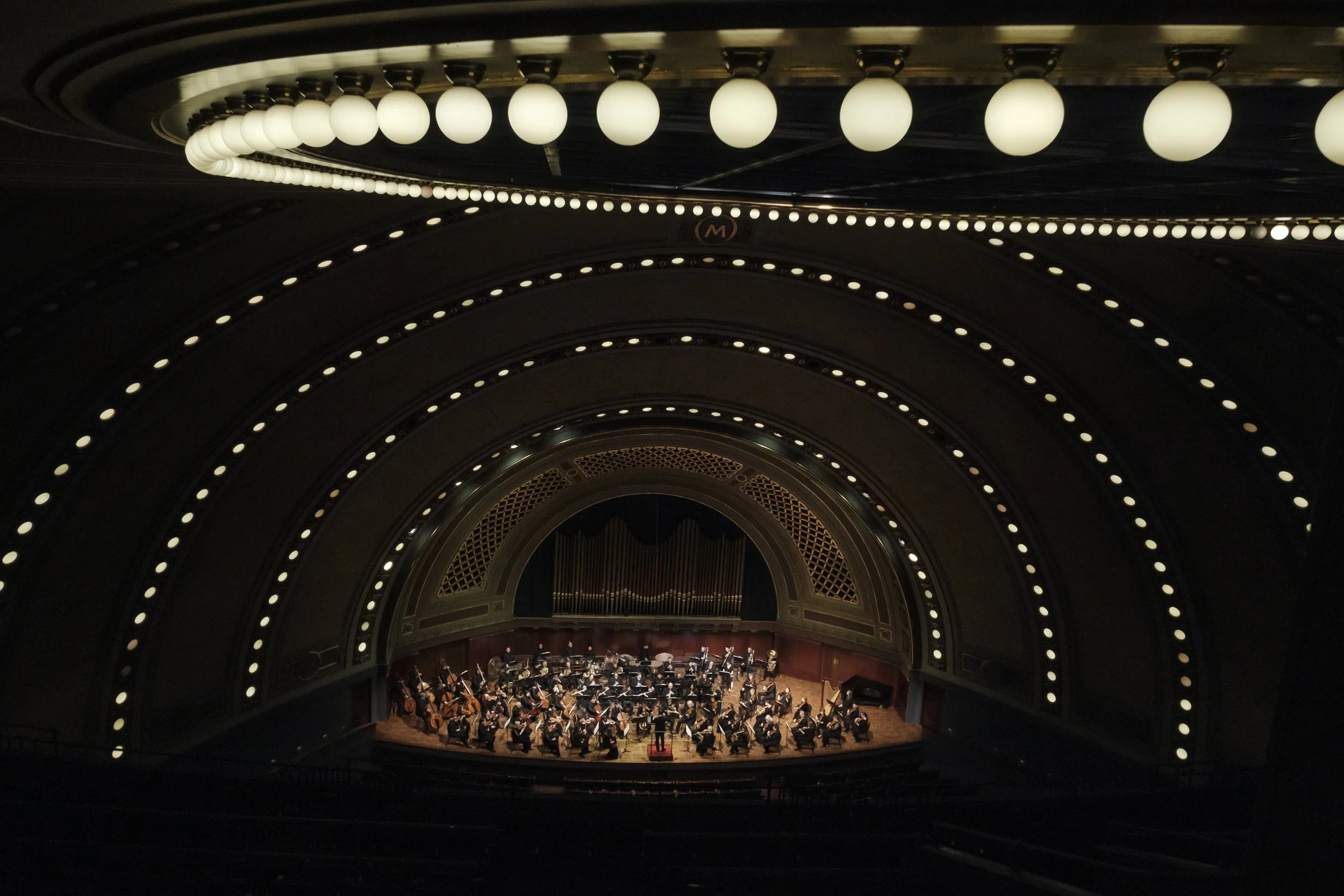 An orchestra on stage shot surrounded by stage lighting