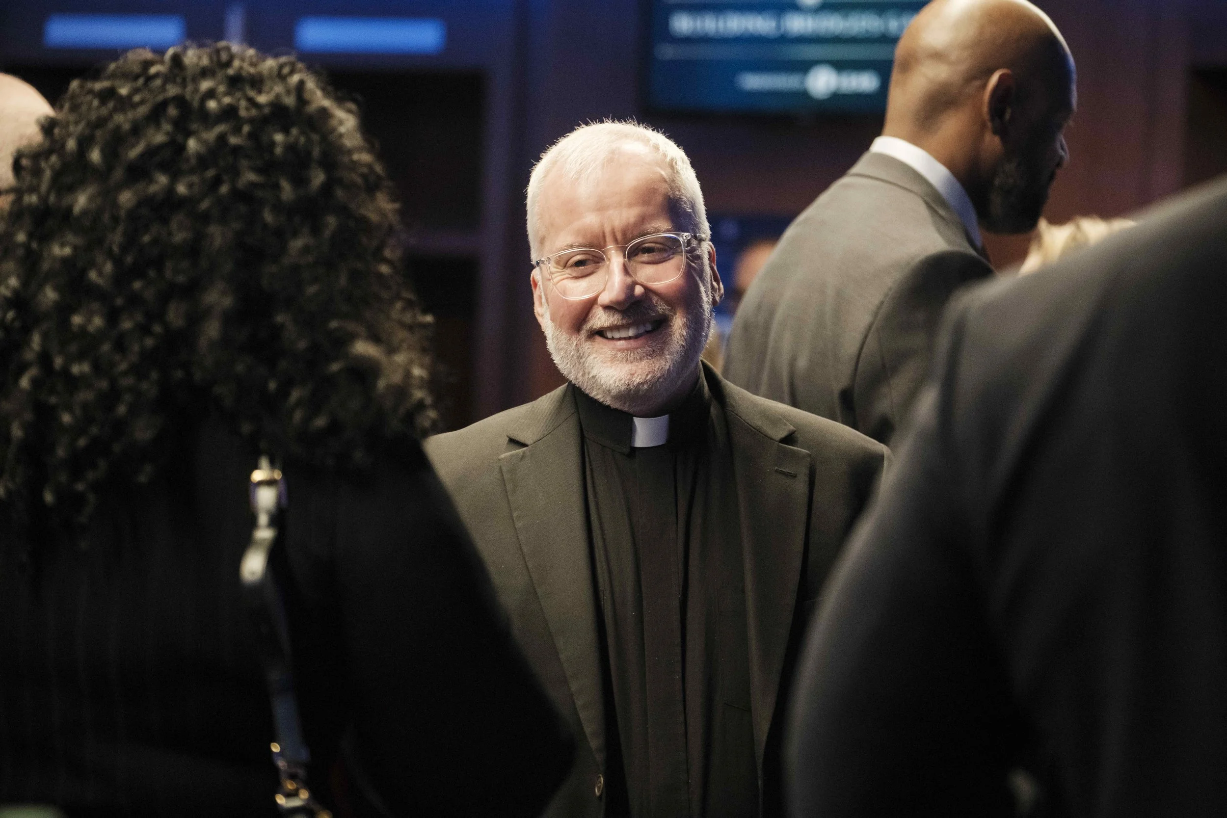 Father Tim smiling and talking with a guest during the Building Bridges Gala