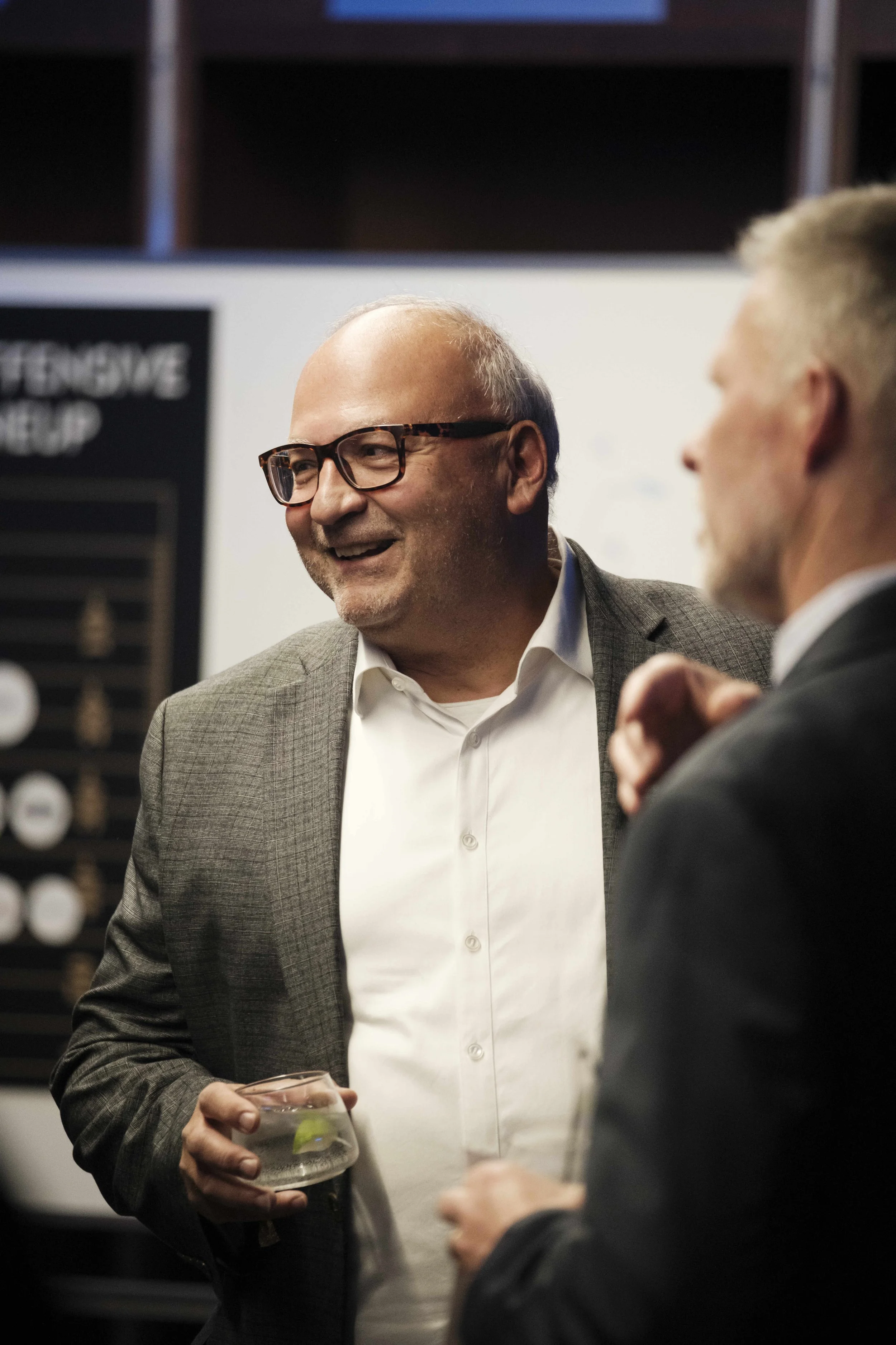 A man wearing glasses, smiles at the Building Bridges Gala.