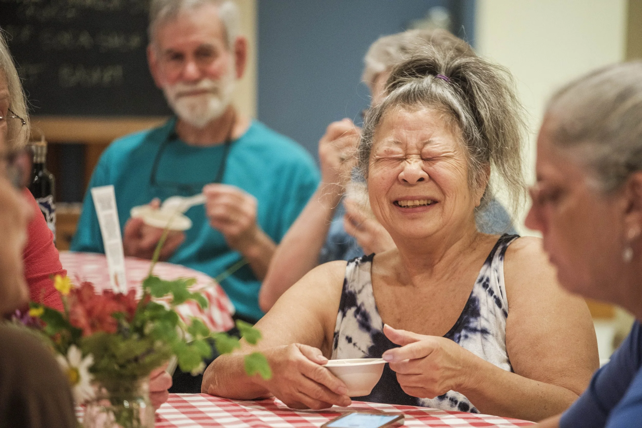 A woman squeezes her eyes shut while holding a paper bowl.