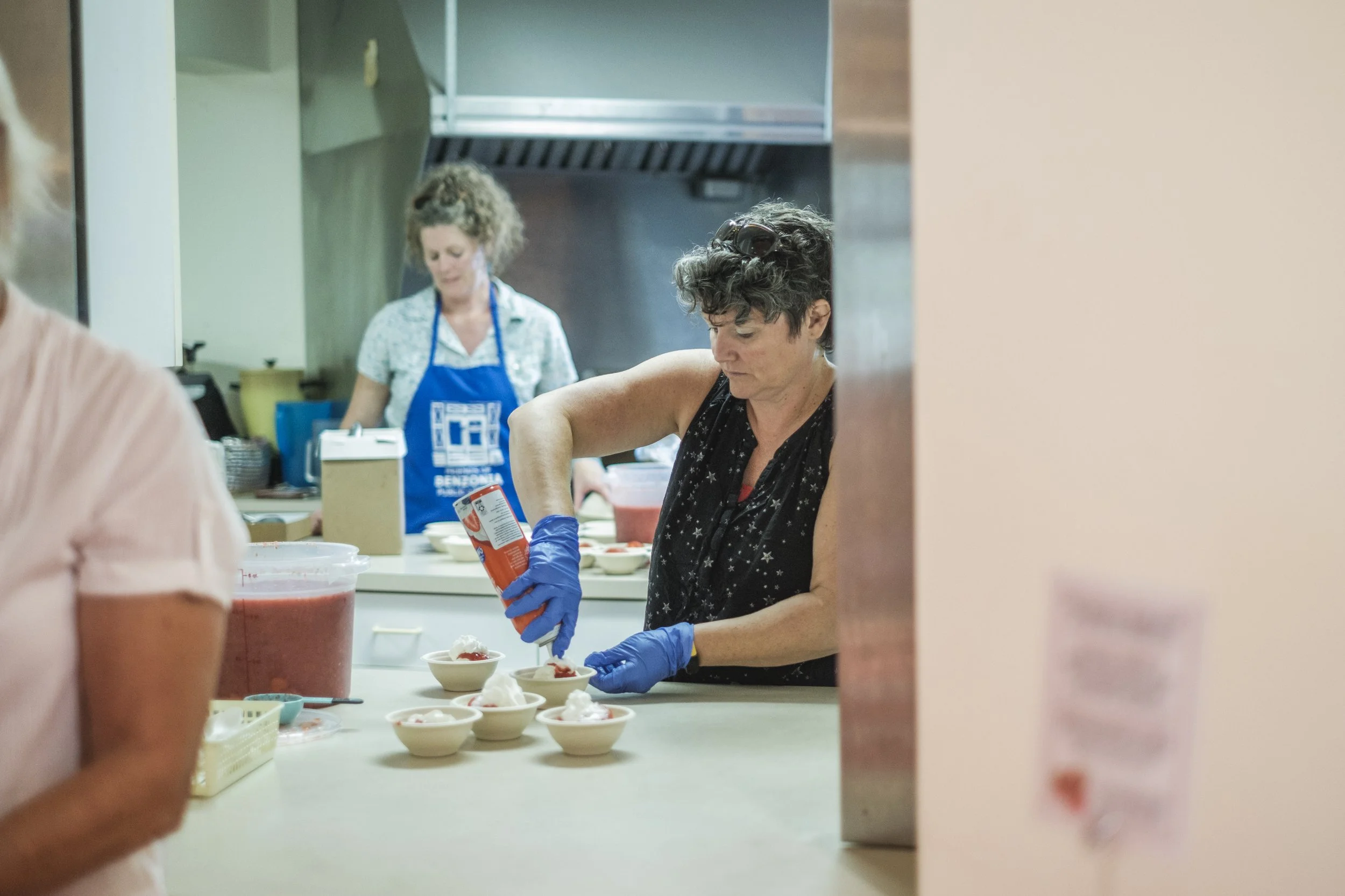 A behind the scenes look into a kitchen of women making strawberry short cake.