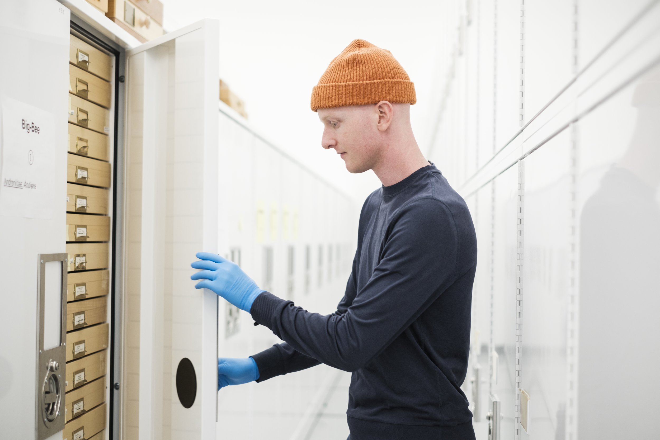 Charlie Engelman opens up a cabinet full of drawers in a white room.