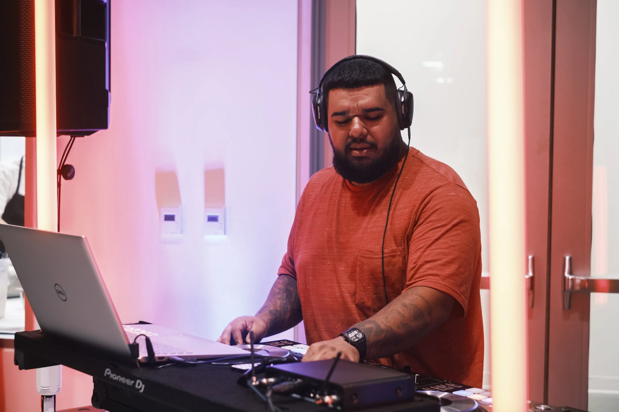 A DJ wears headphones and closes his eyes while playing music at an event.