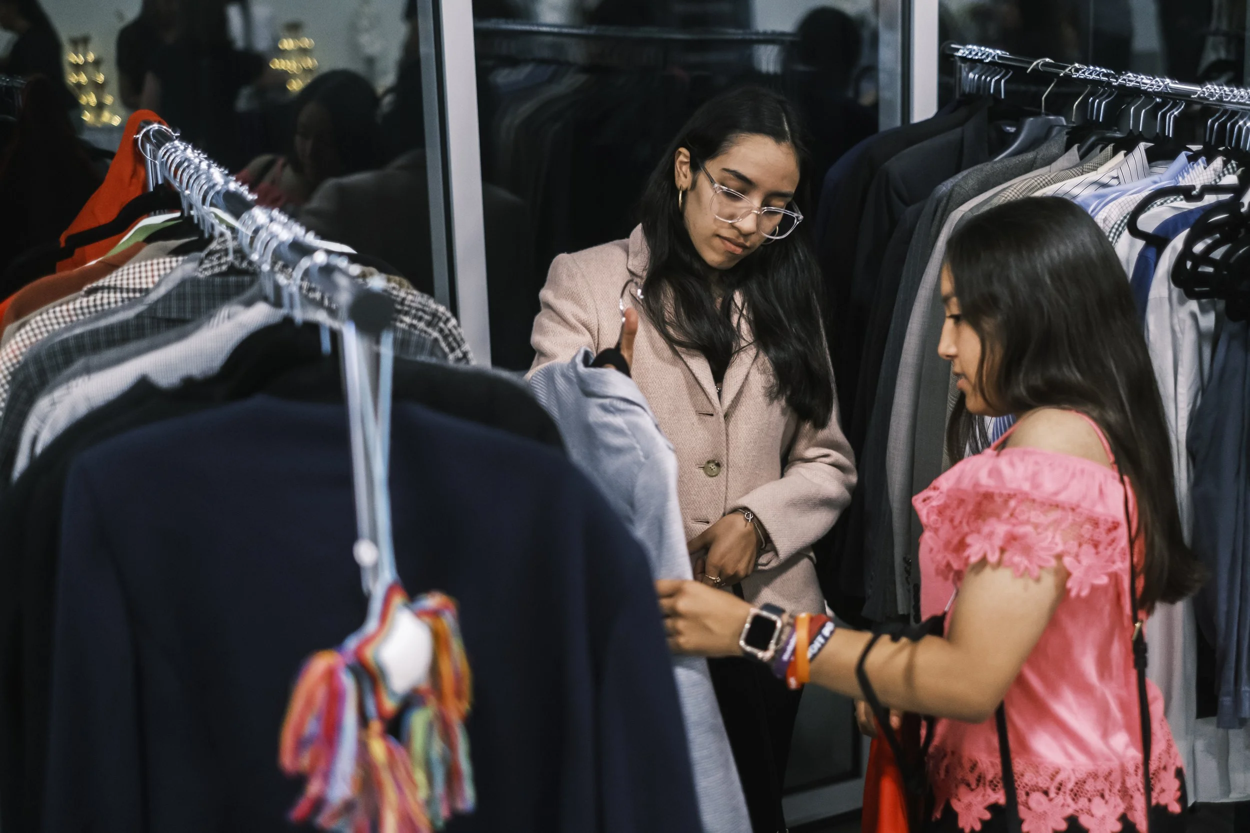 Two young women look through clothing racks.