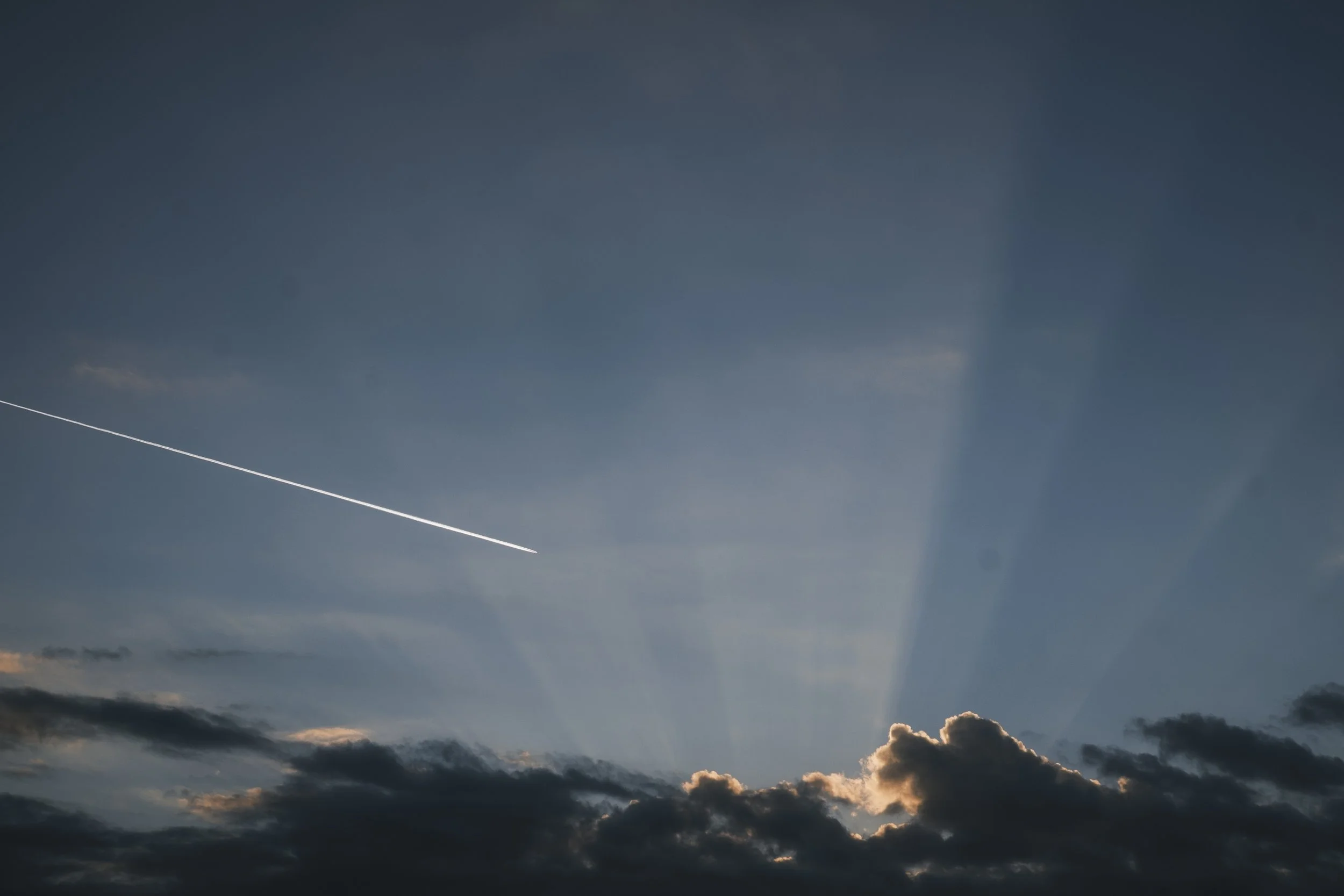 A trail made from an airplane flying above clouds in the evening at Grand Marais, MI
