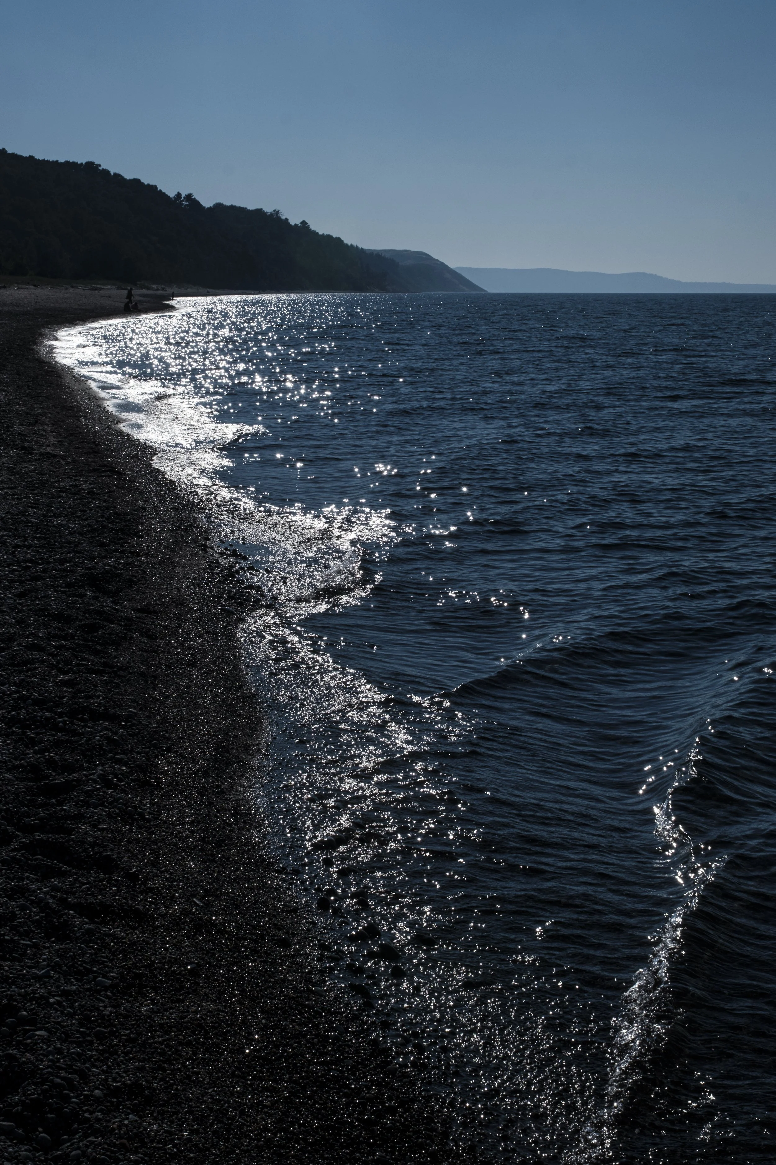 Sparkling water running along the short of a beach in Agate beach looking towards Grand Sable Dunes and Pictured Rocks National Lakeshore in Grand Marais, MI