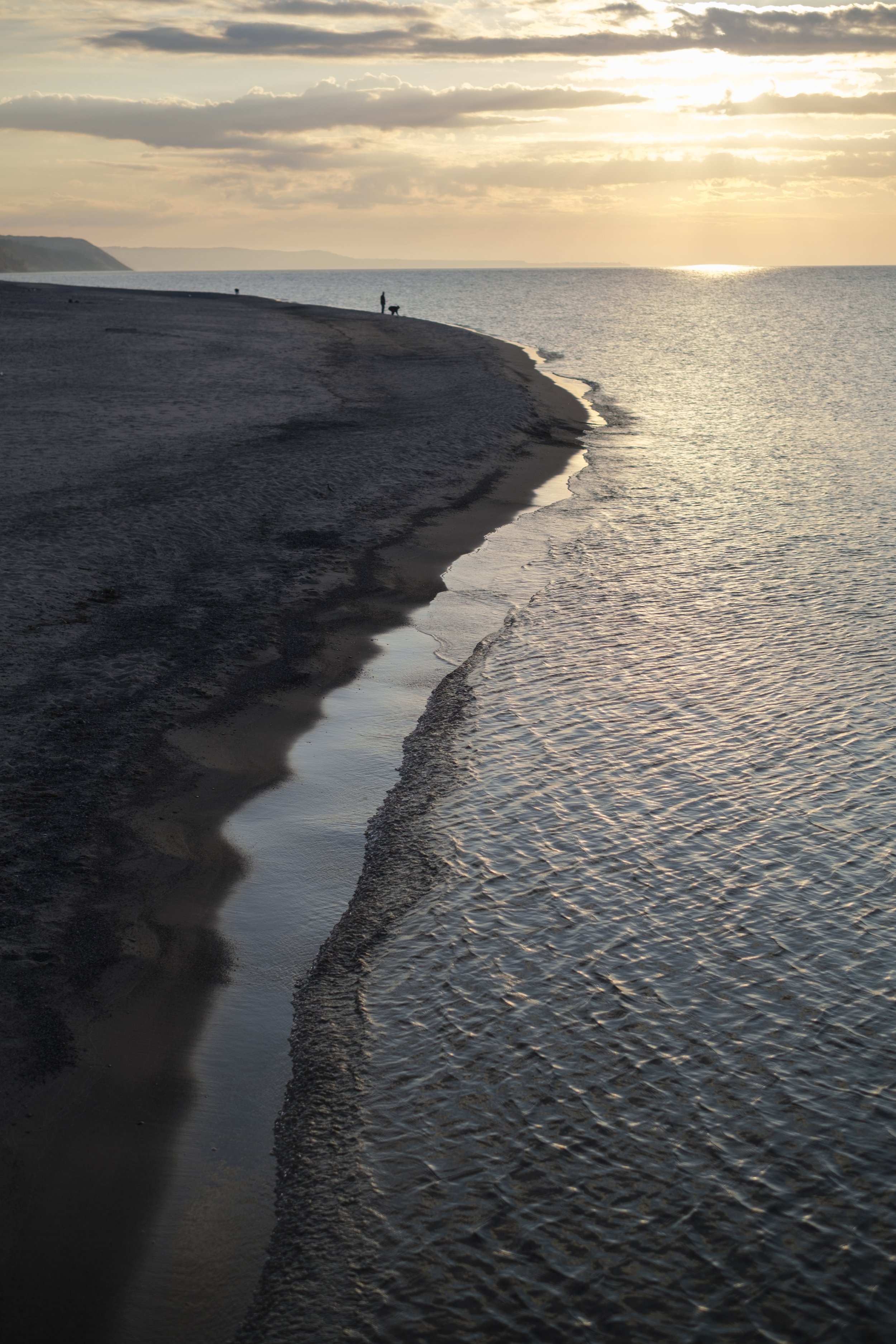 A person with their dog are silhouetted on shores of Lake Superior in Grand Marais, MI