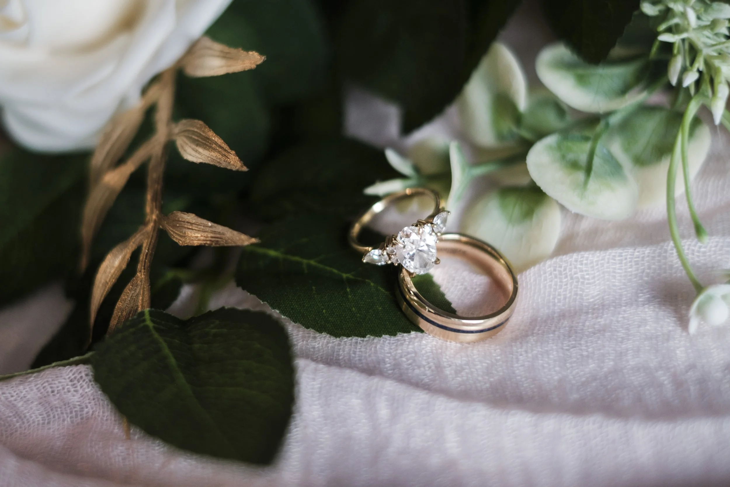 Two rings lay against flowers.