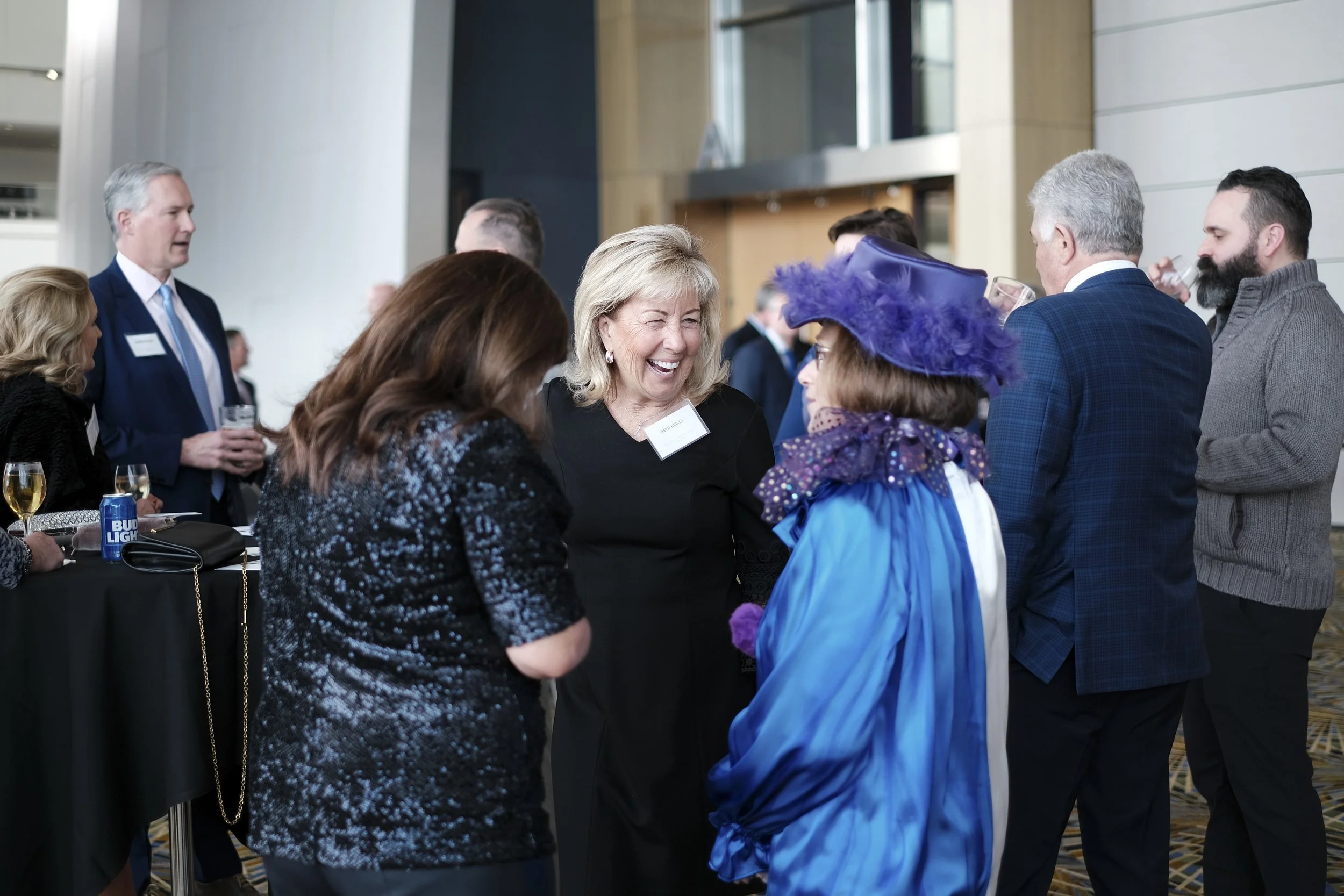 A woman wearing a blue dress laughs between two women.n