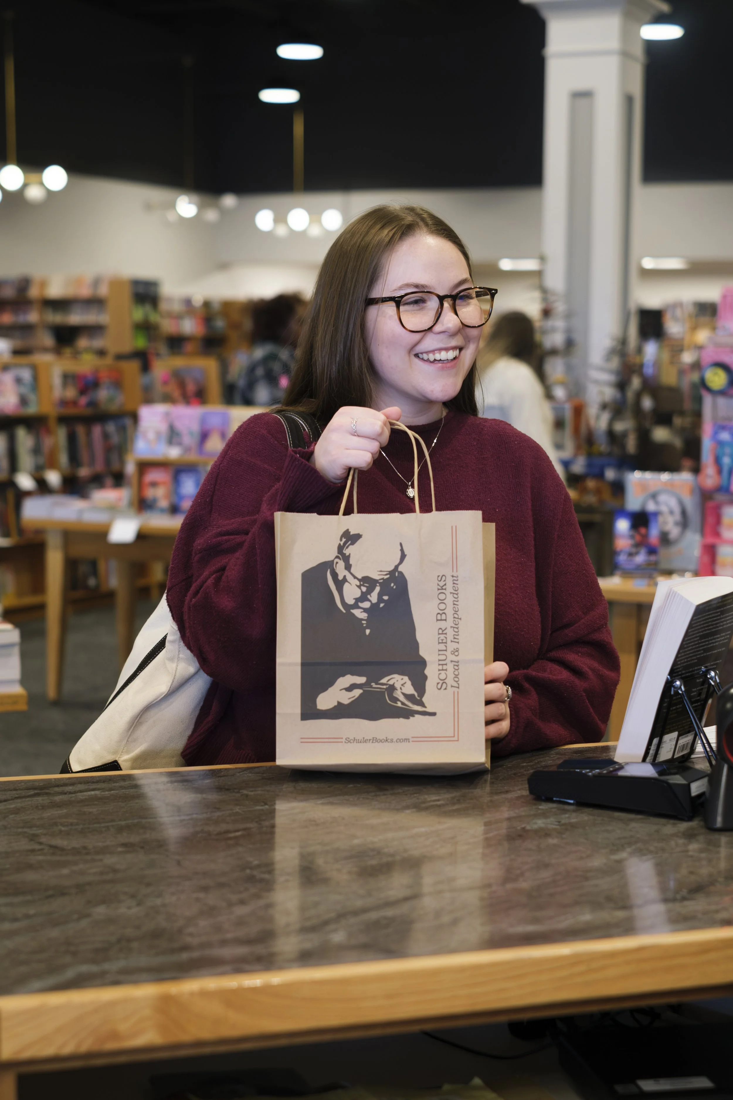 A woman smiles while at the check out counter at Schuler Books in West Bloomfield, Michigan.