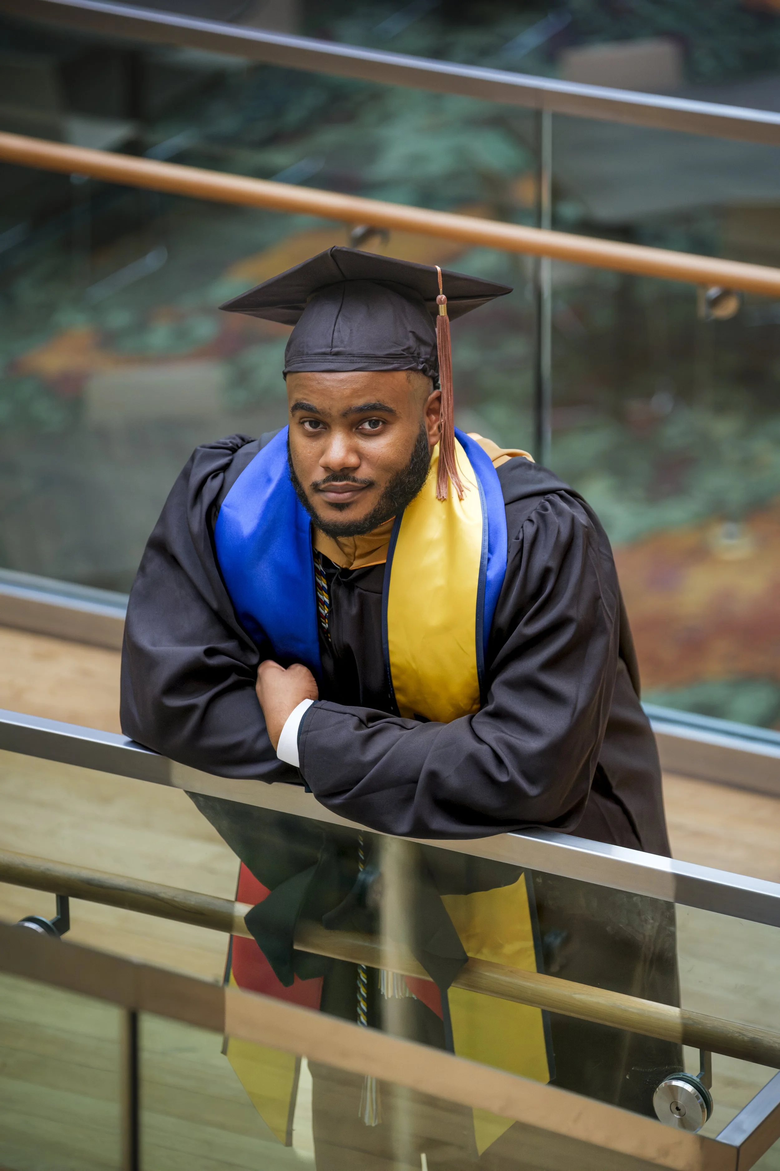 A man smiles while wearing his Commencement Cap and Gown on the campus of the University of Michigan at the Ross School of Business in Ann Arbor.