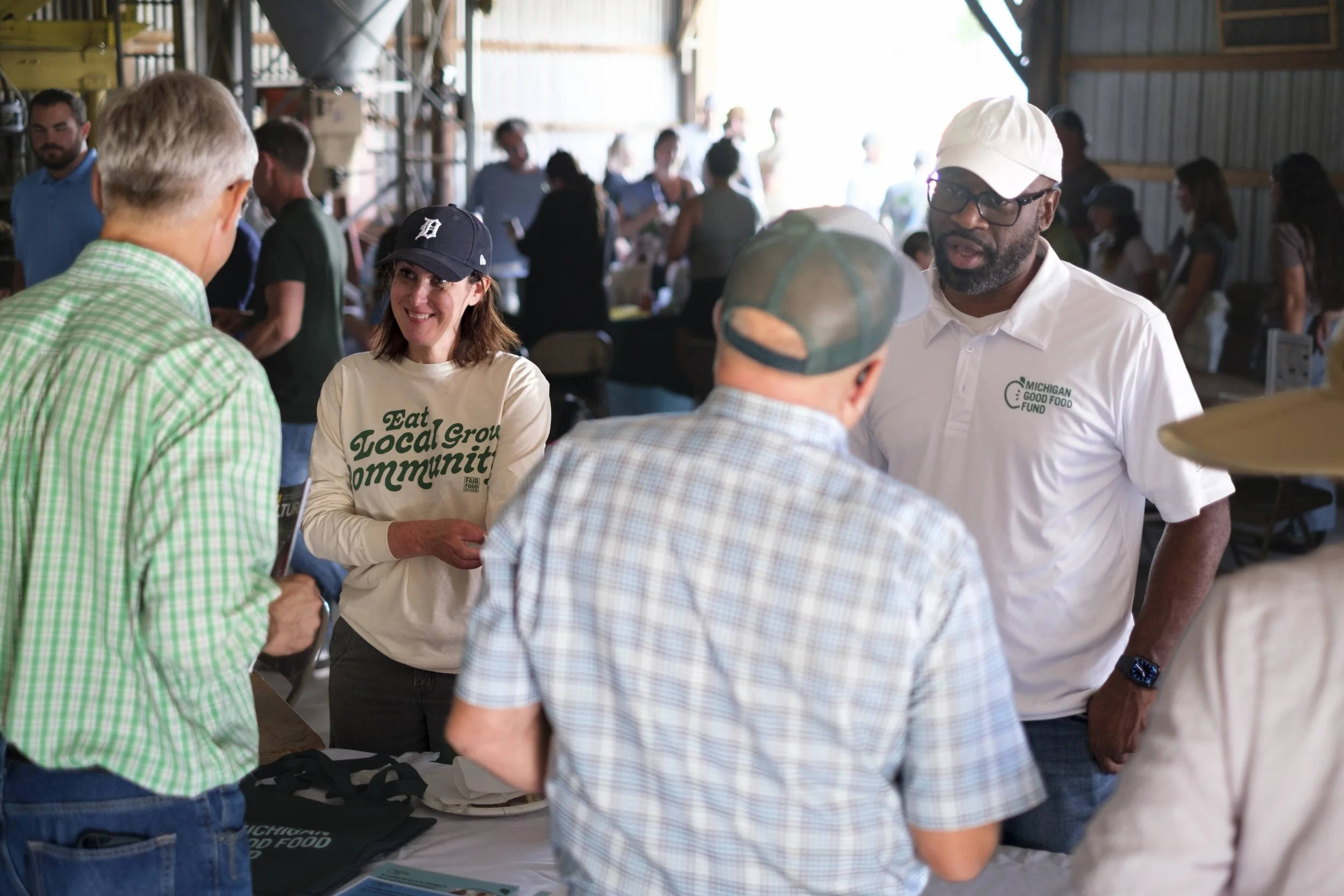 A group of people talk to one another at an information table during the Washtenaw County Conservation District's Farmer Field Day.