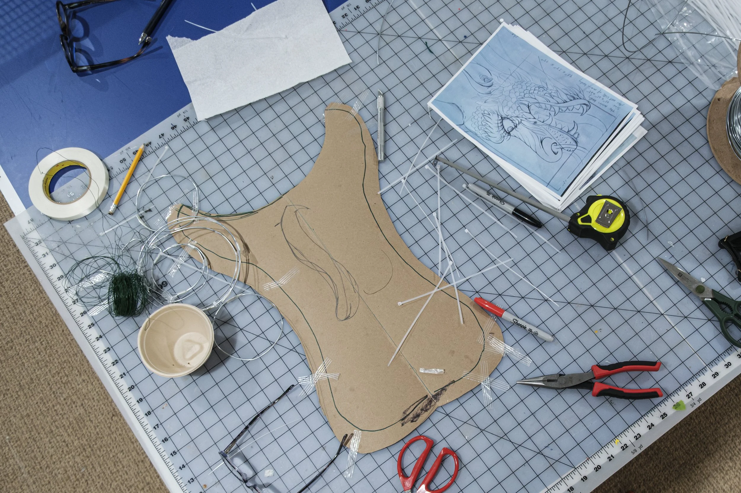 Metal wire, tape, scissors and other art materials lay on a table.