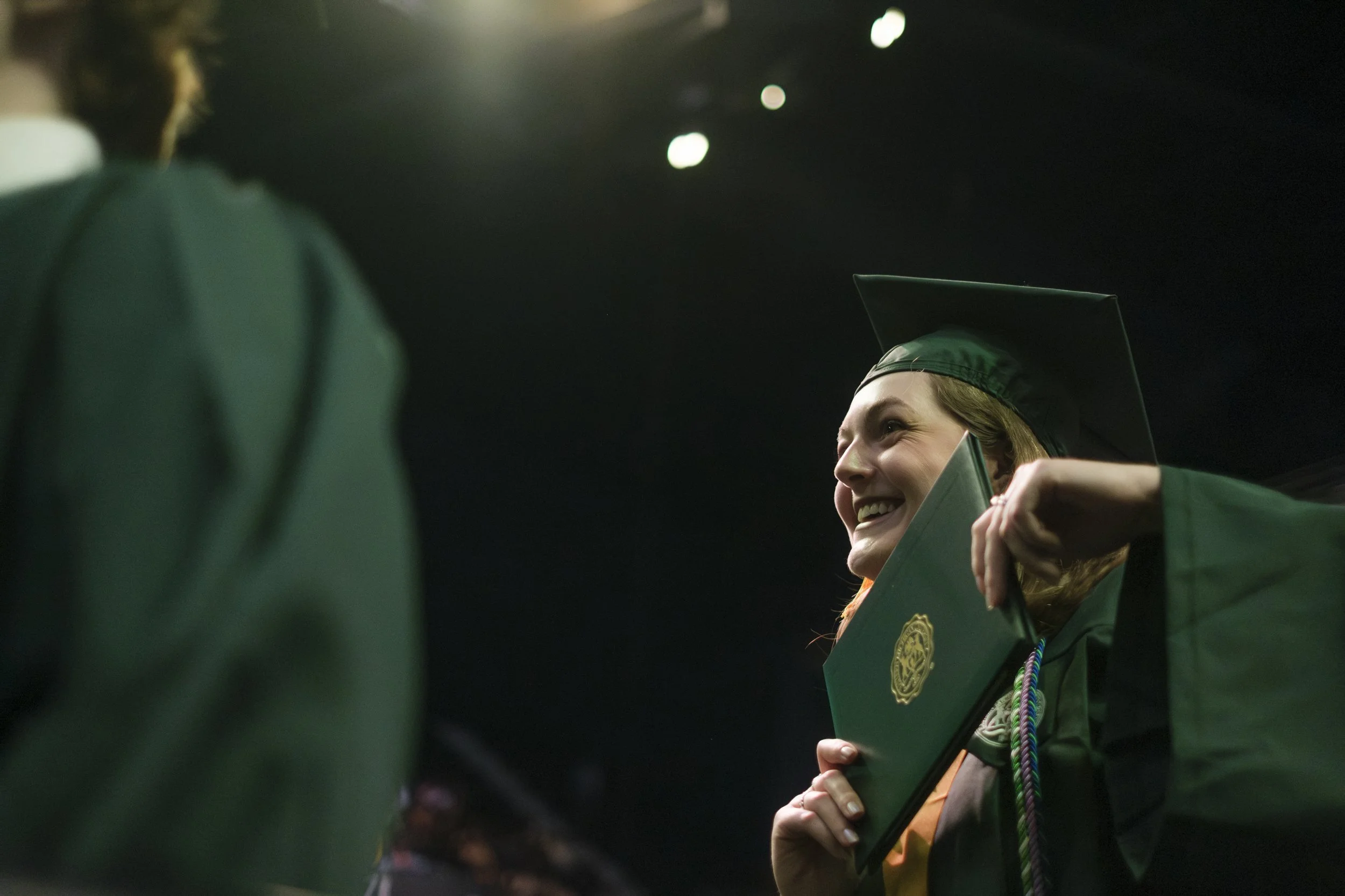a person holding their diploma up near their chin and smiles.