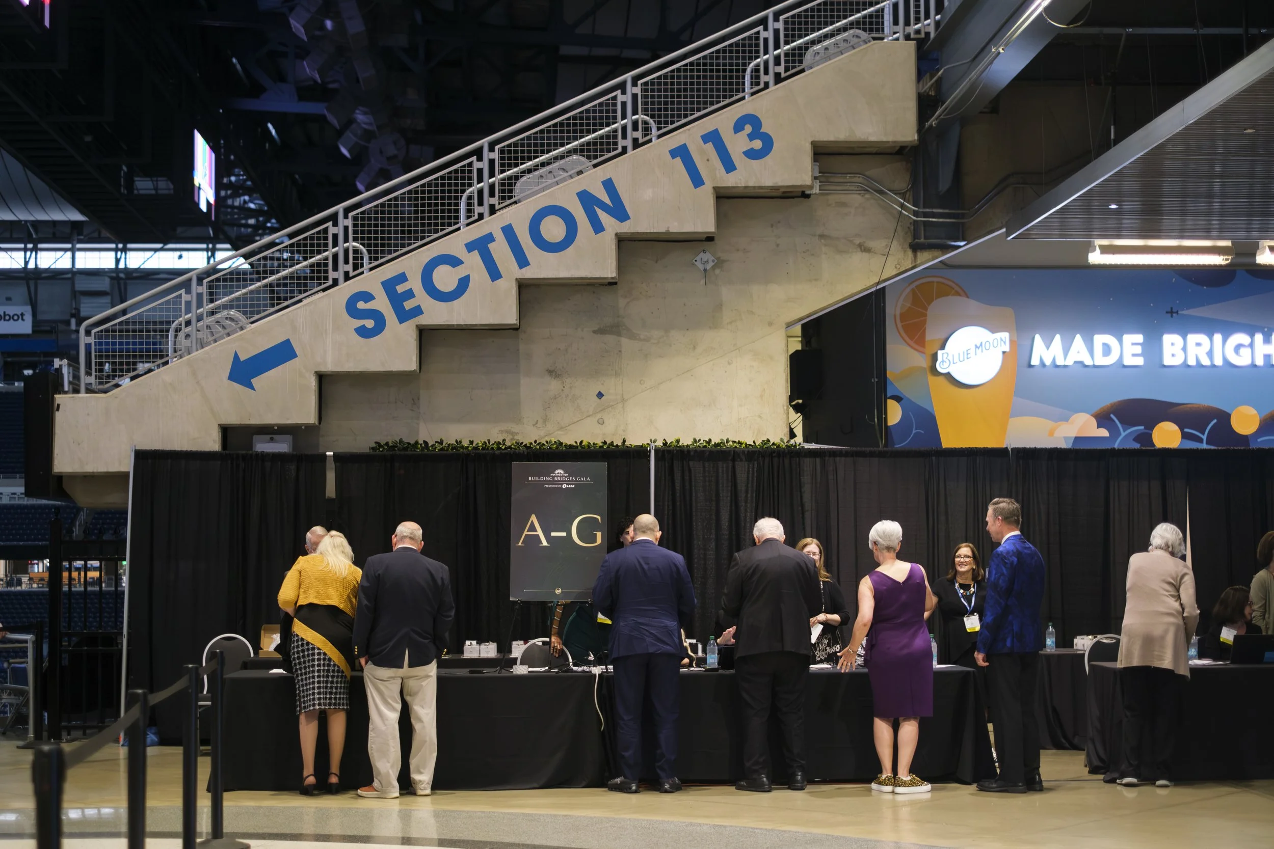 A line of people wearing suits and dresses check in ahead of the Building Bridges Gala at Ford Field in Detroit.