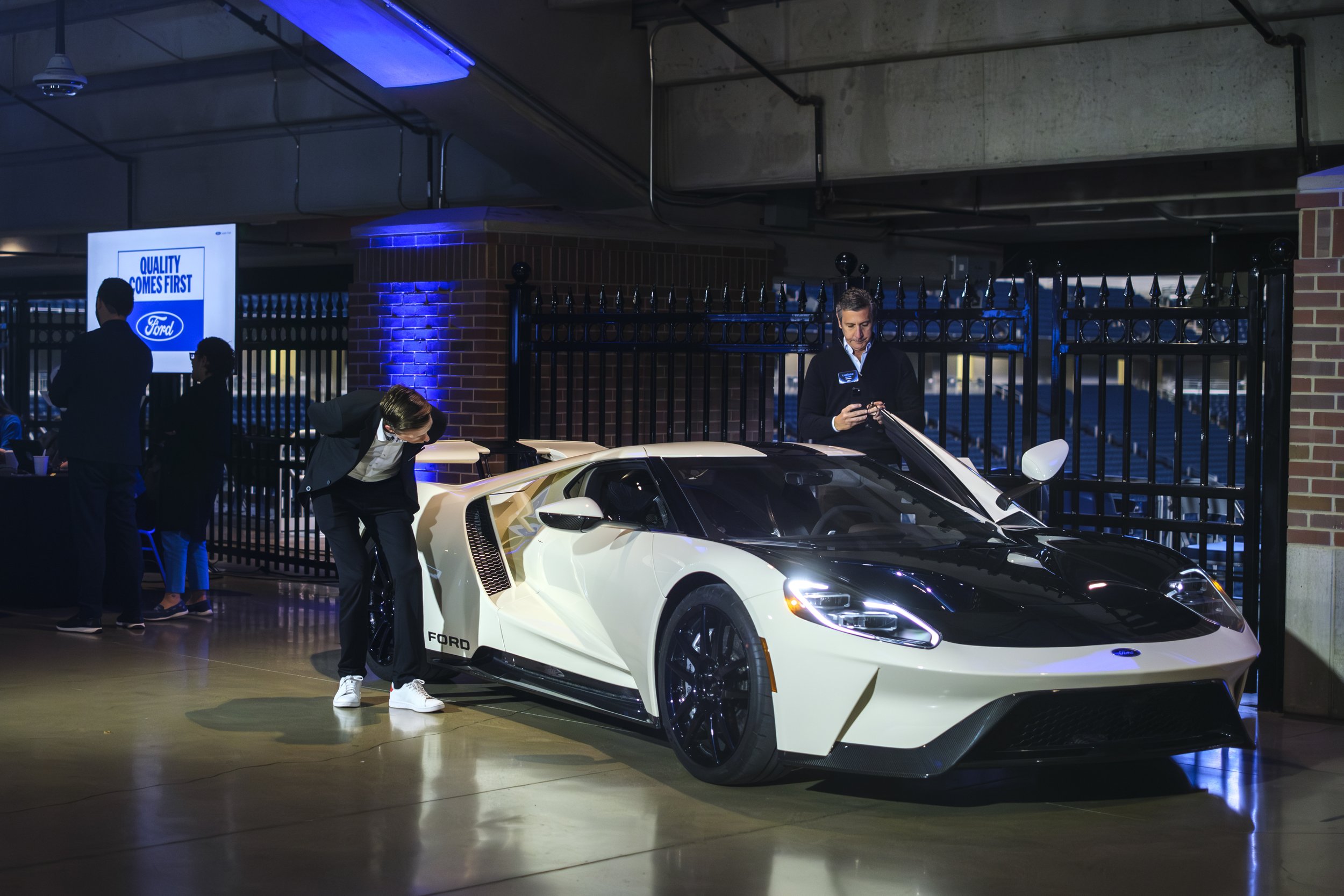Two men inspect a Ford GT that is on display in the corridor of Ford Field during the Ford Supplier Summit.