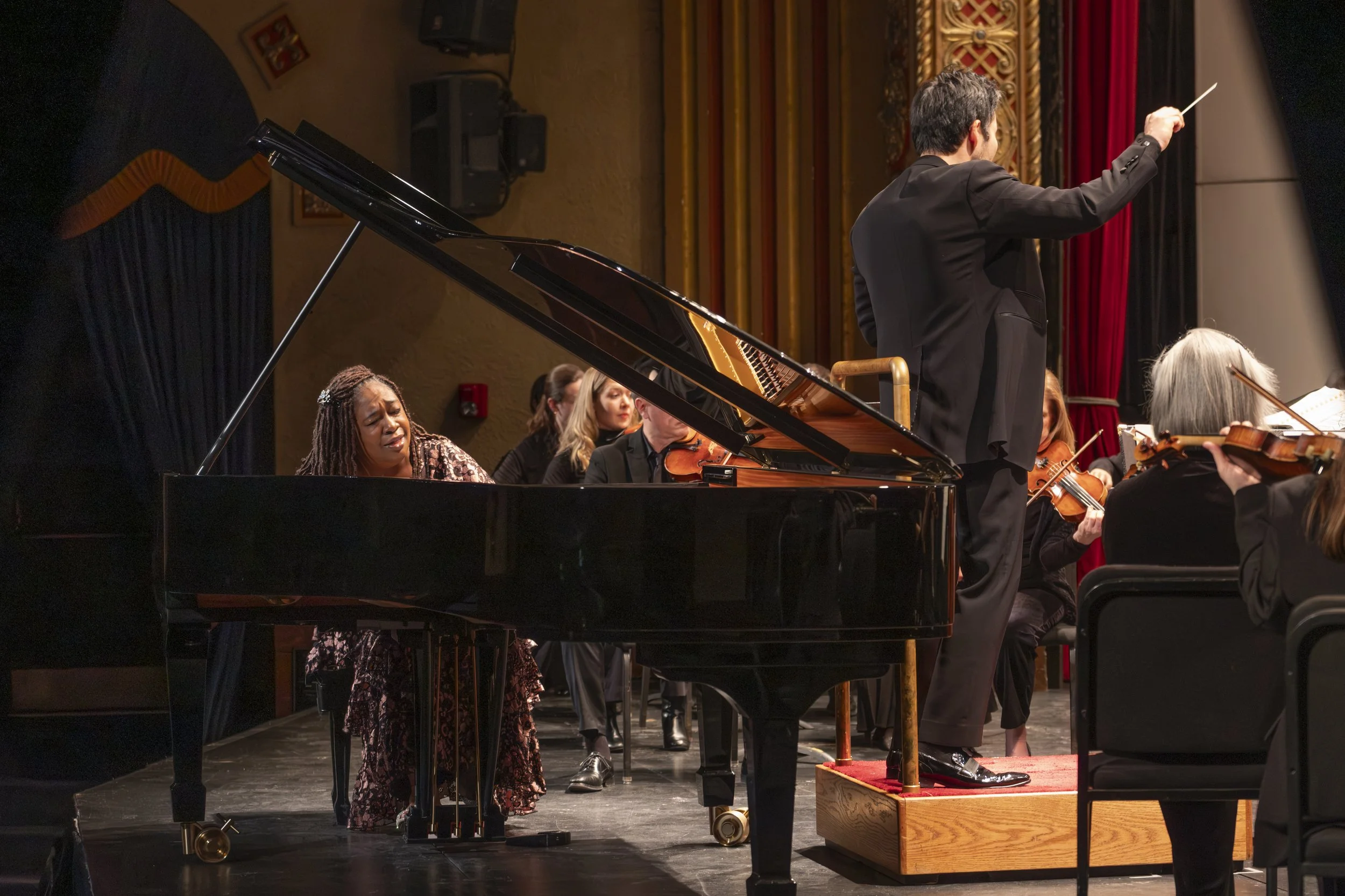 Pianist Michelle Cann plays the piano on stage while the Ann Arbor Symphony Orchestra plays behind her.