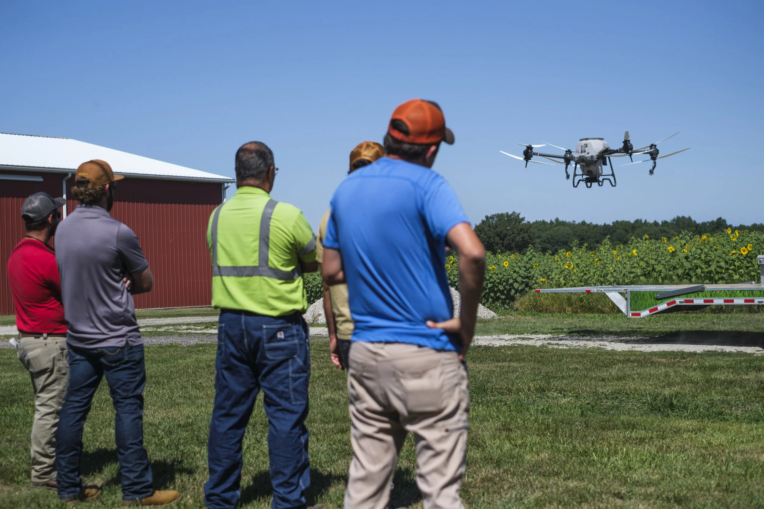 A group of people stand and watch a drone take off during a live demonstration during the Washtenaw County Conservation District's Farmer Field Day.