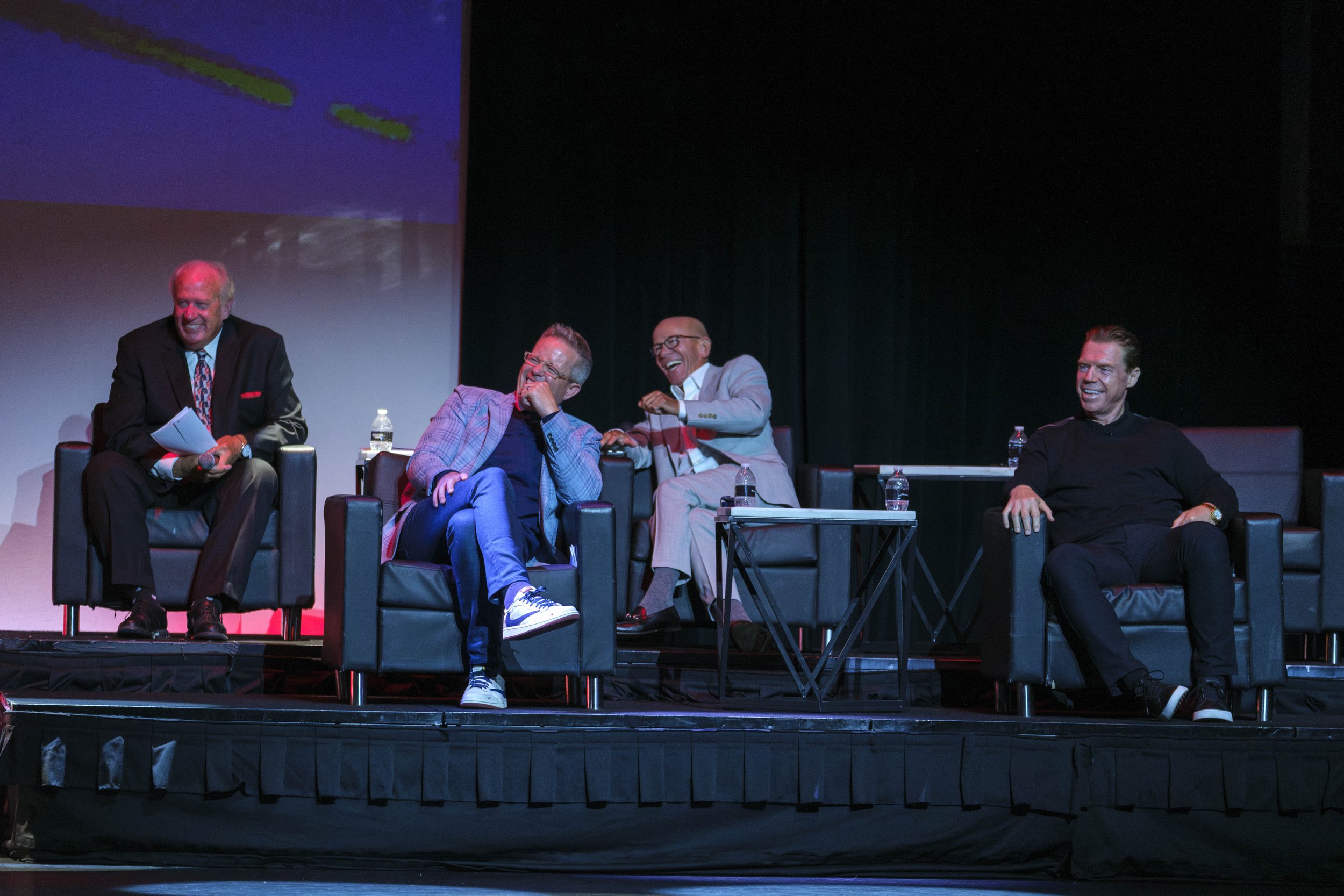 Kris Draper, Darren Pang, Neil Little and John Keating sit in chairs on a stage and laugh during the Roast of Chris Osgood.
