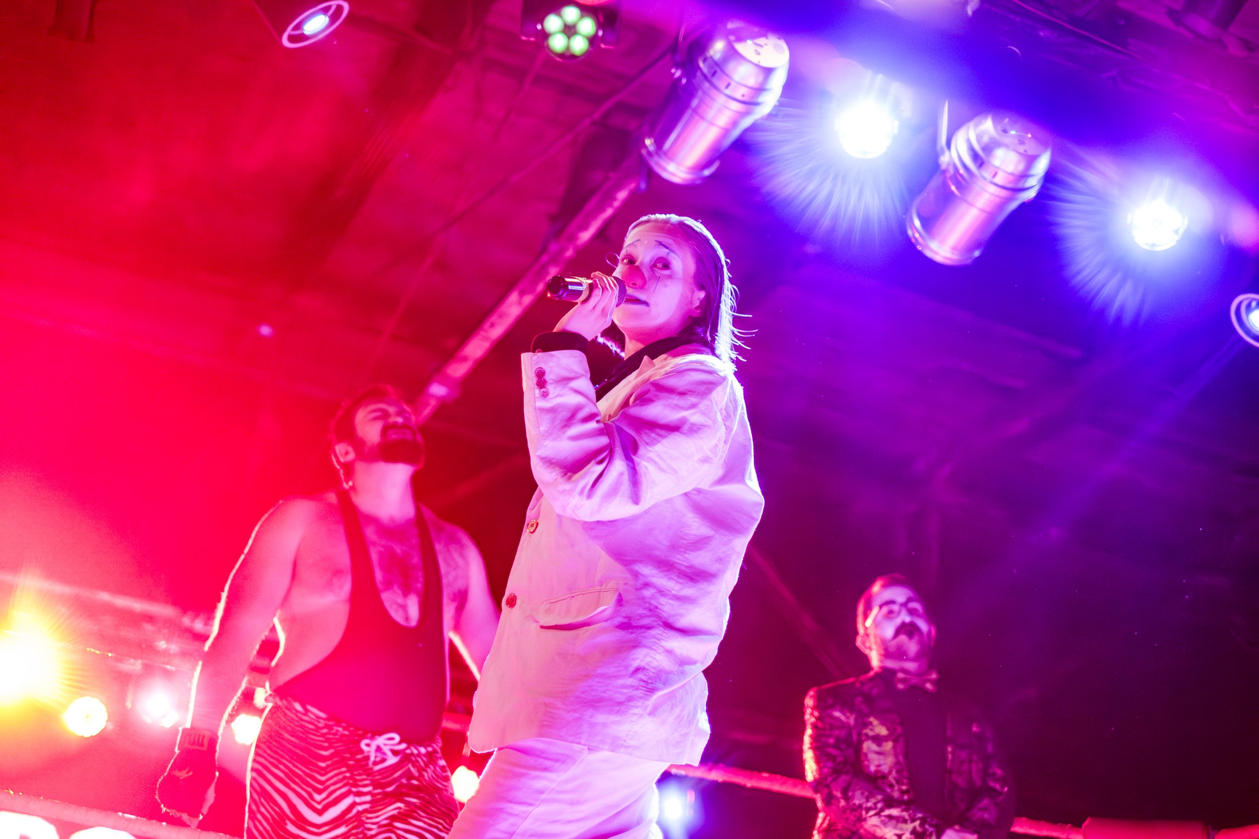 Clown wrestler Don Bozo hold a microphone in a wrestling ring.