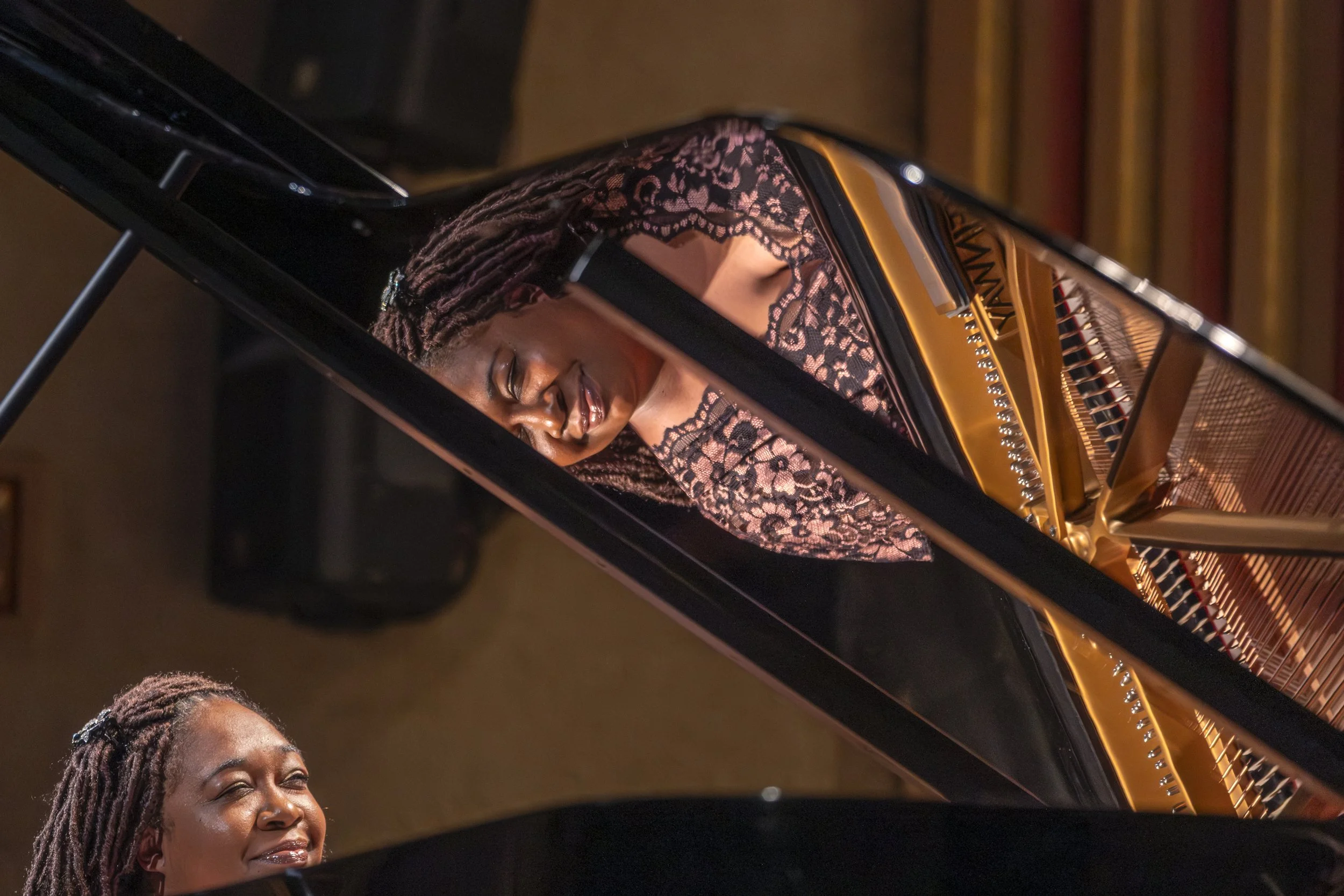 A pianist is reflected in the inner lid of a grand piano