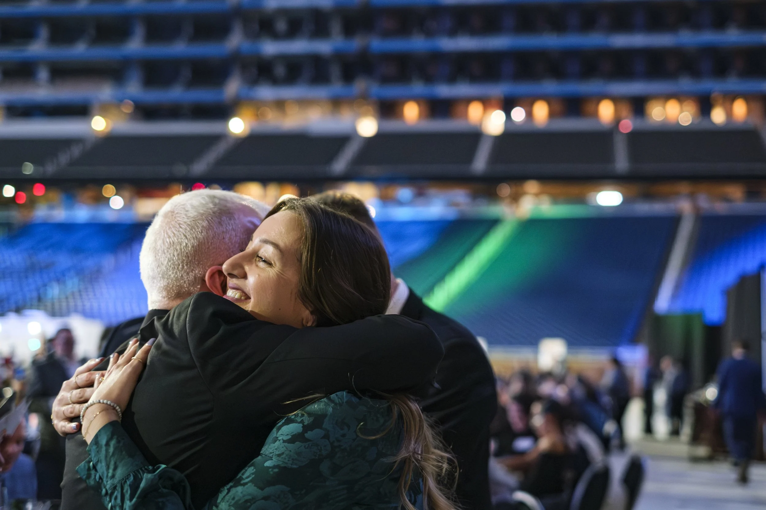 A woman wearing a dress and man wearing a suit hug one another during the Building Bridges Gala at Ford Field.