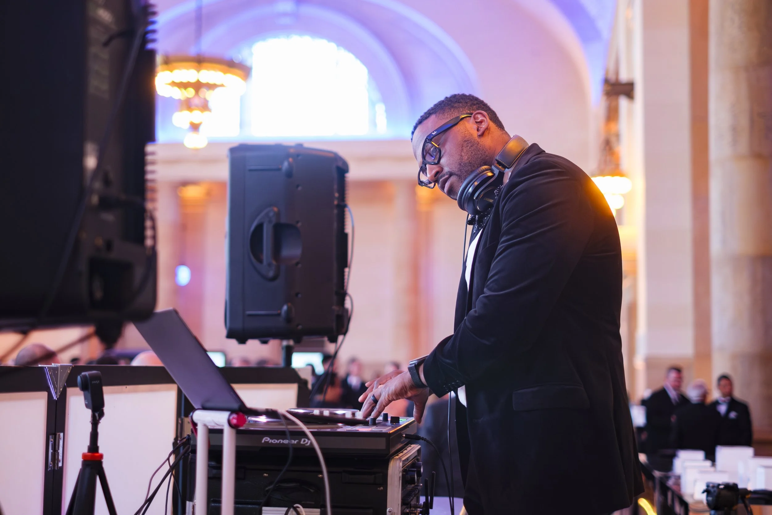 A DJ looks at his laptop while headphones sit around his neck while playing music for guests during the Ford Supplier Summit Awards at Michigan Central Station in Detroit, Michigan.