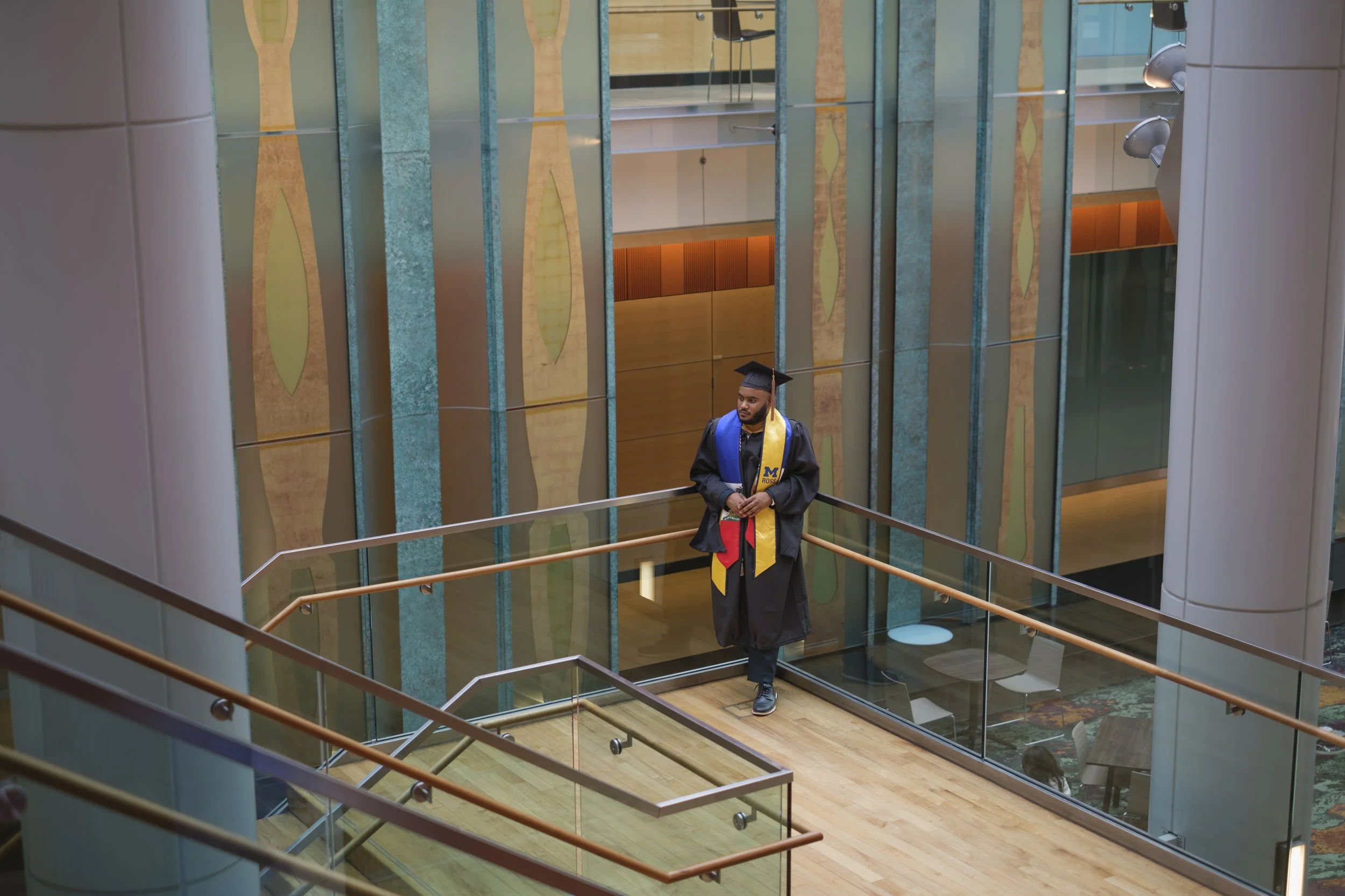 A graduate from the University of Michigan stands on a stairway in the Ross School of Business on the campus of the University of Michigan.