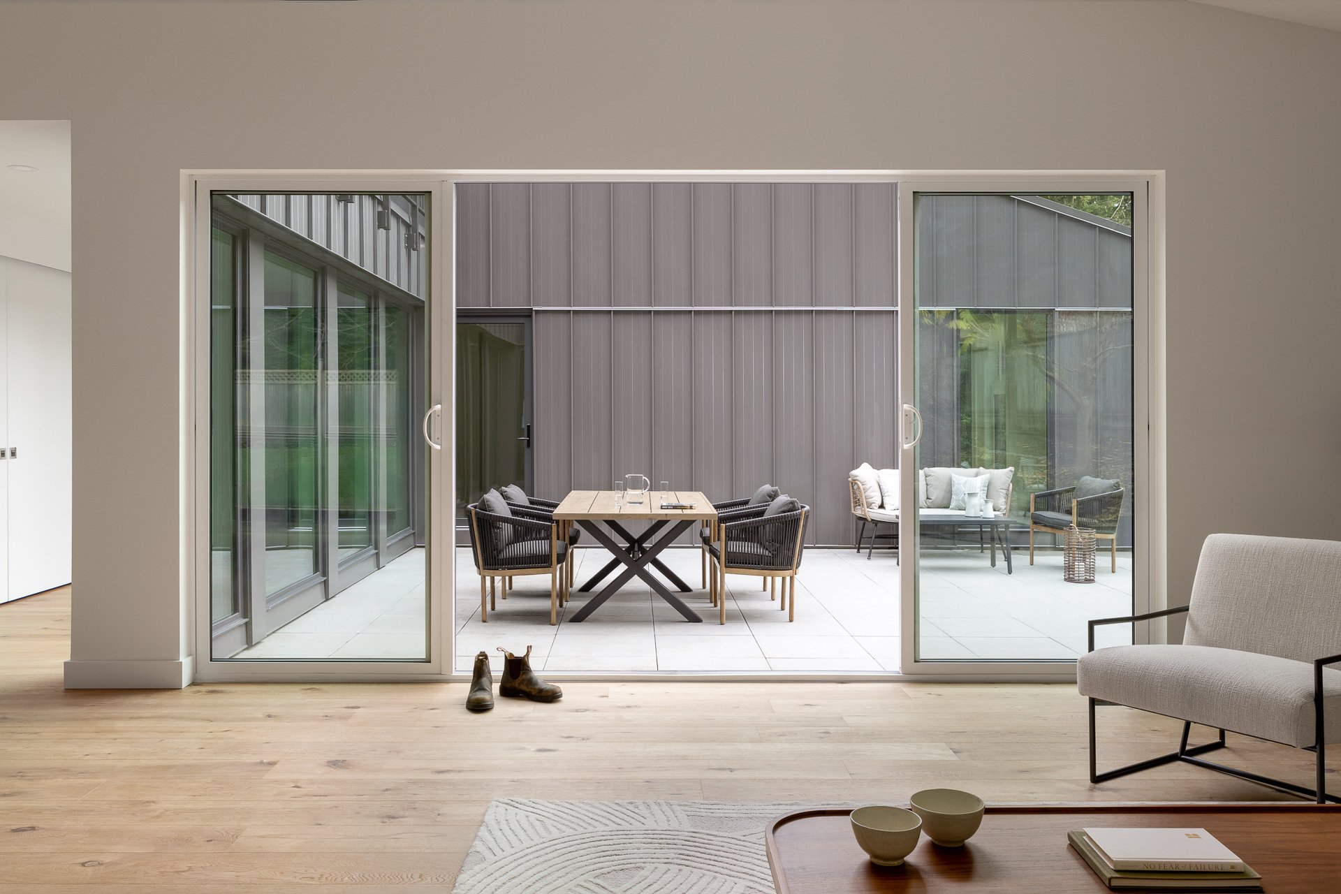 Living room with a large sliding glass door opening to a patio with outdoor furniture and a gray wall.