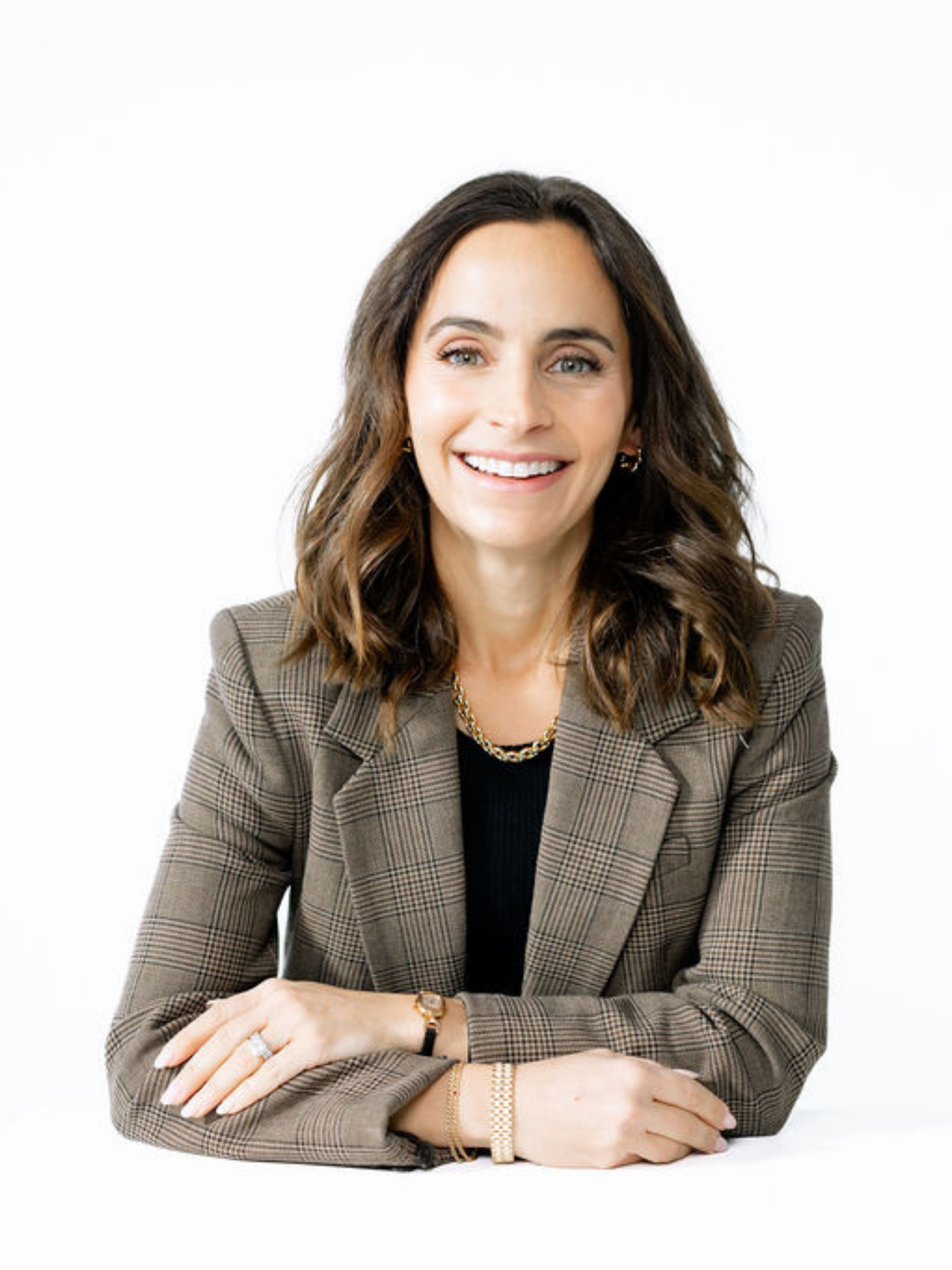 A brunette woman smiling wearing a professional brown blazer.