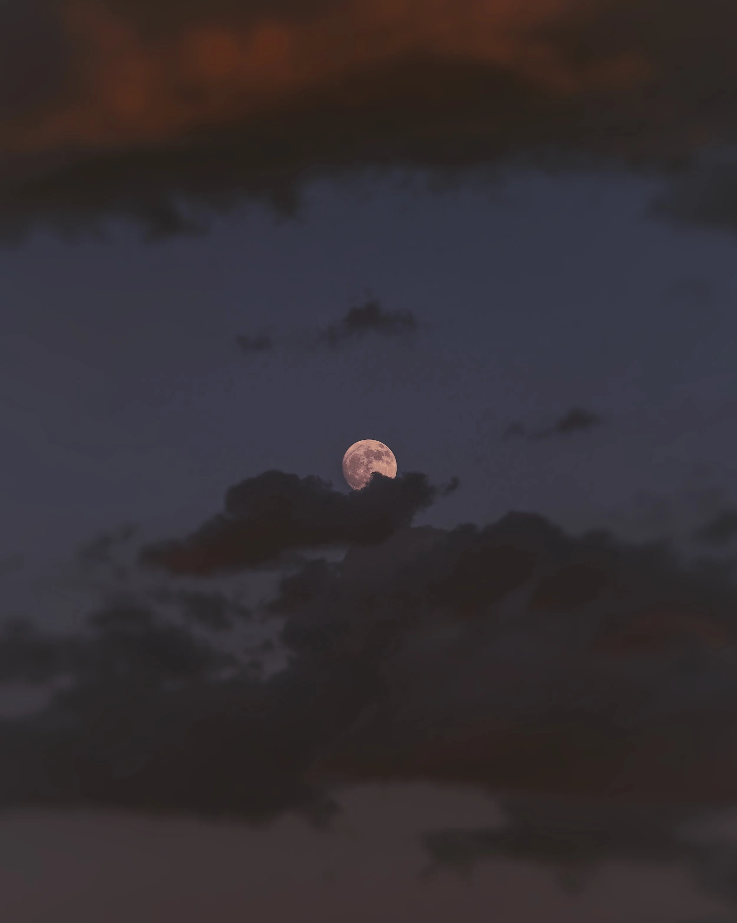 Night sky with dark clouds and a visible full moon.