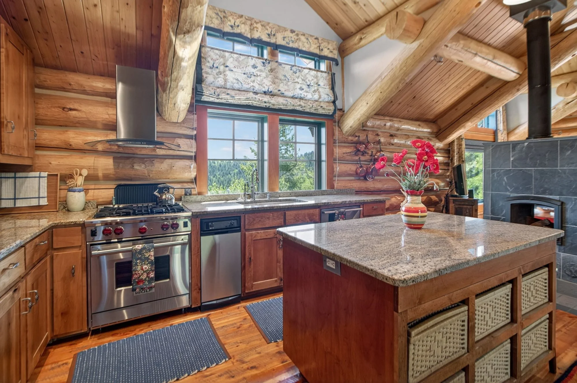 Kitchen with log walls, a timber ceiling and a large island in the Hidden Hills log home
