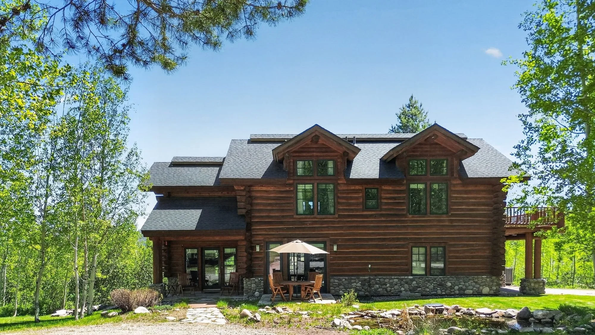 Exterior of the Hidden Hills log home on a sunny summer day in Wilson, Wyoming