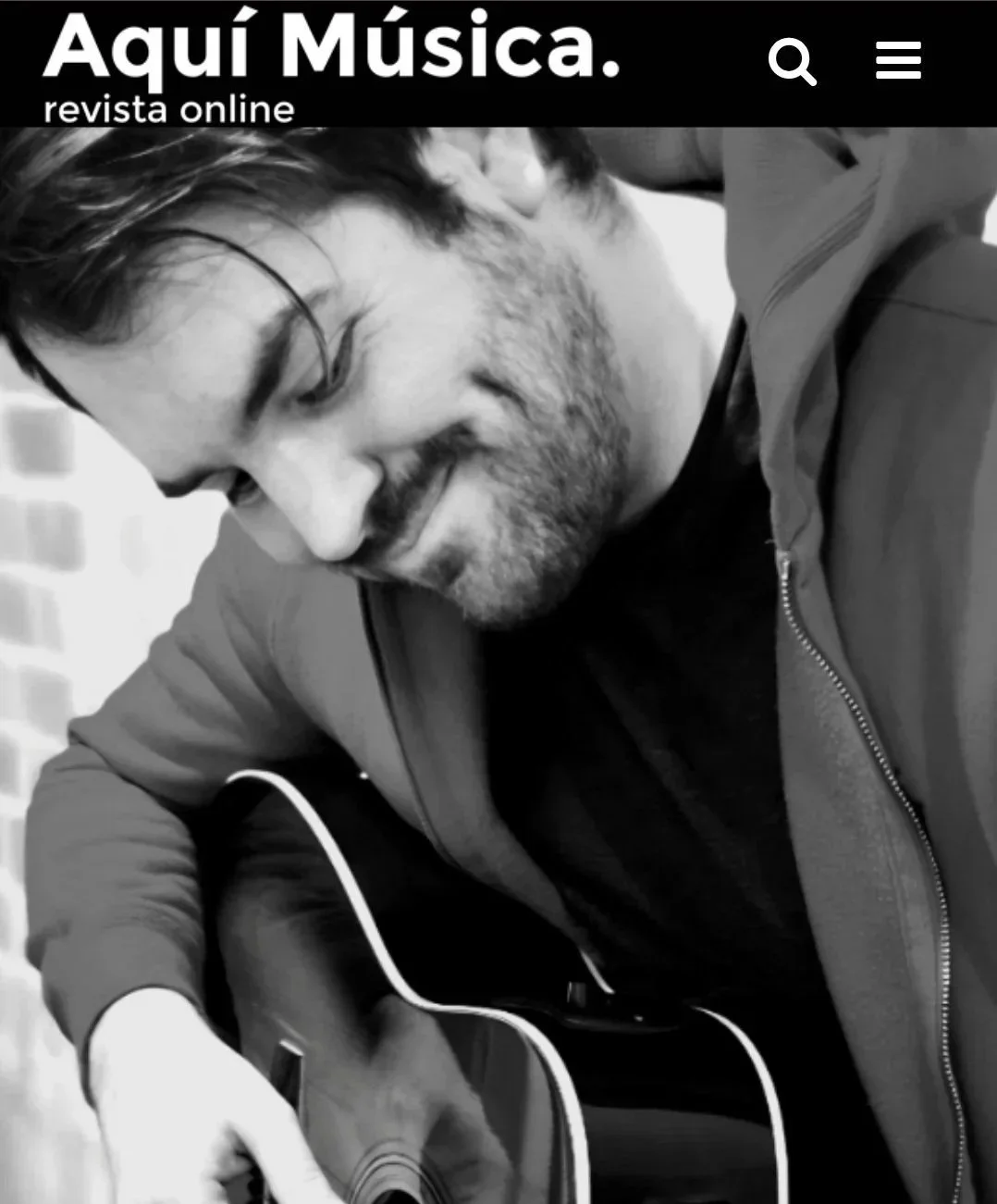 the Music artist Tomas Rosas is seen with his guitar for an album review of his 2026 debut album Dos Latidos. The revie is by Aqui Musica