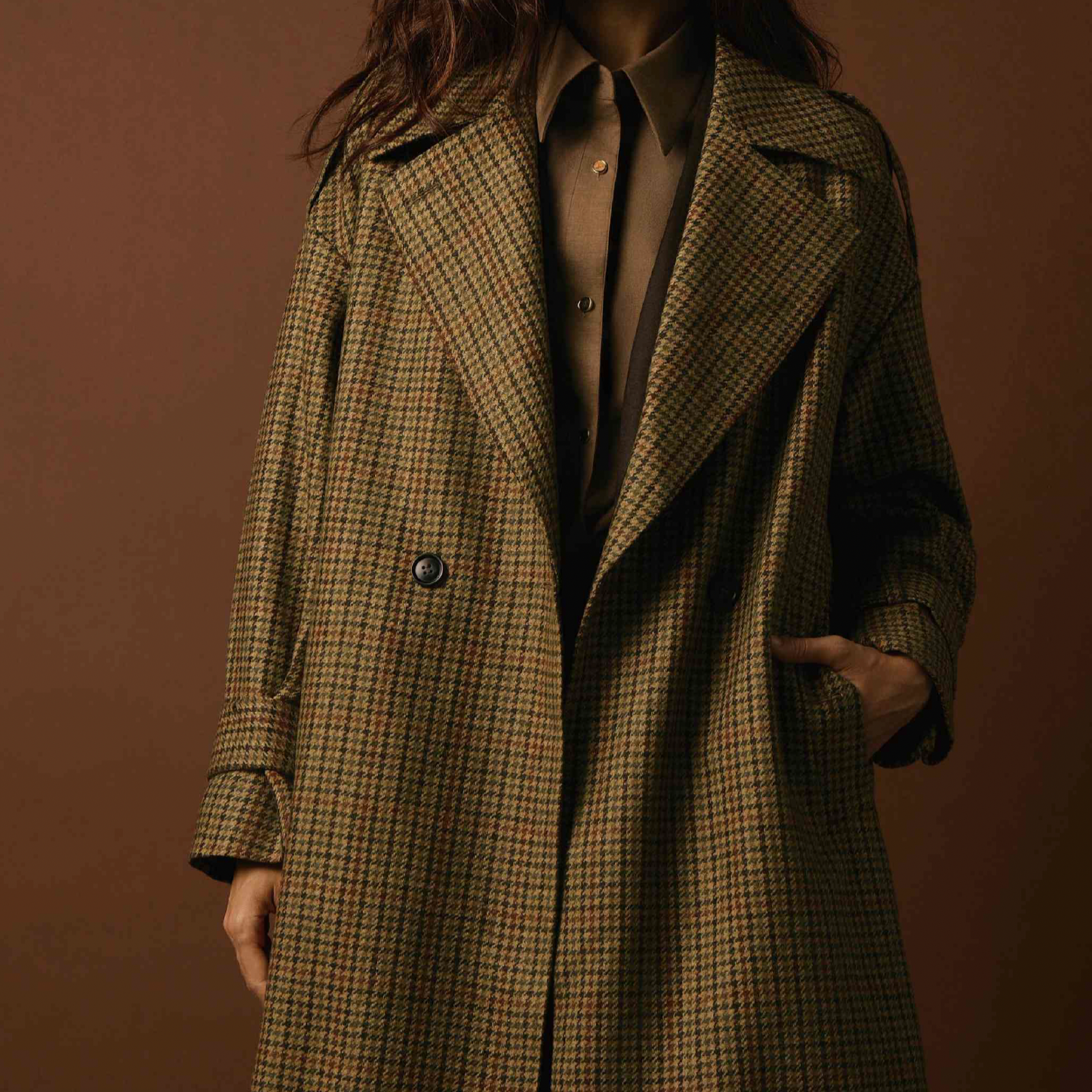 Women's Tailored custom made  Person wearing a checkered long coat and a gray shirt with a black collar against a brown background.